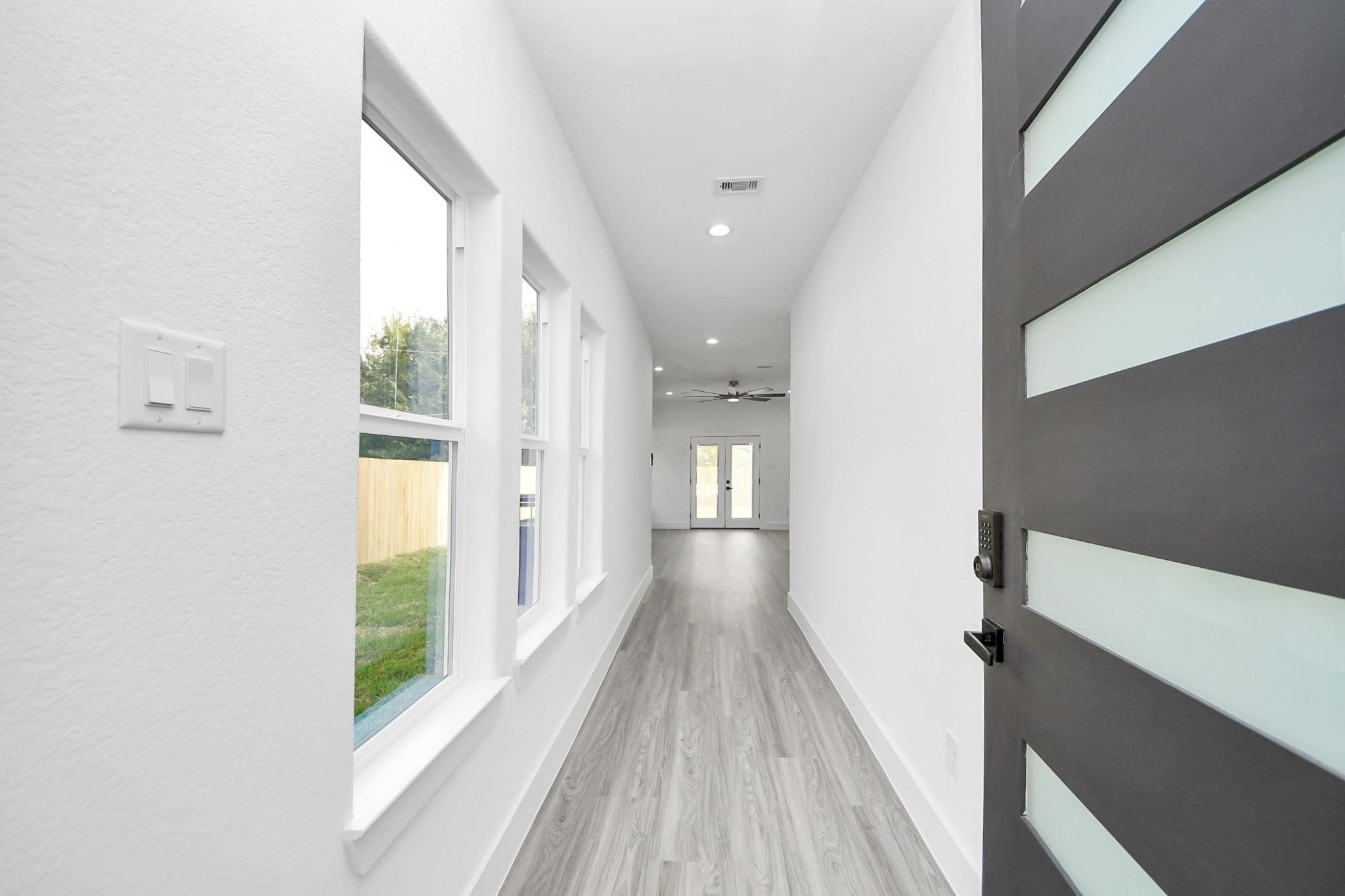 Sleek entryway with modern door and abundant natural light, leading to an open living space with stylish flooring.