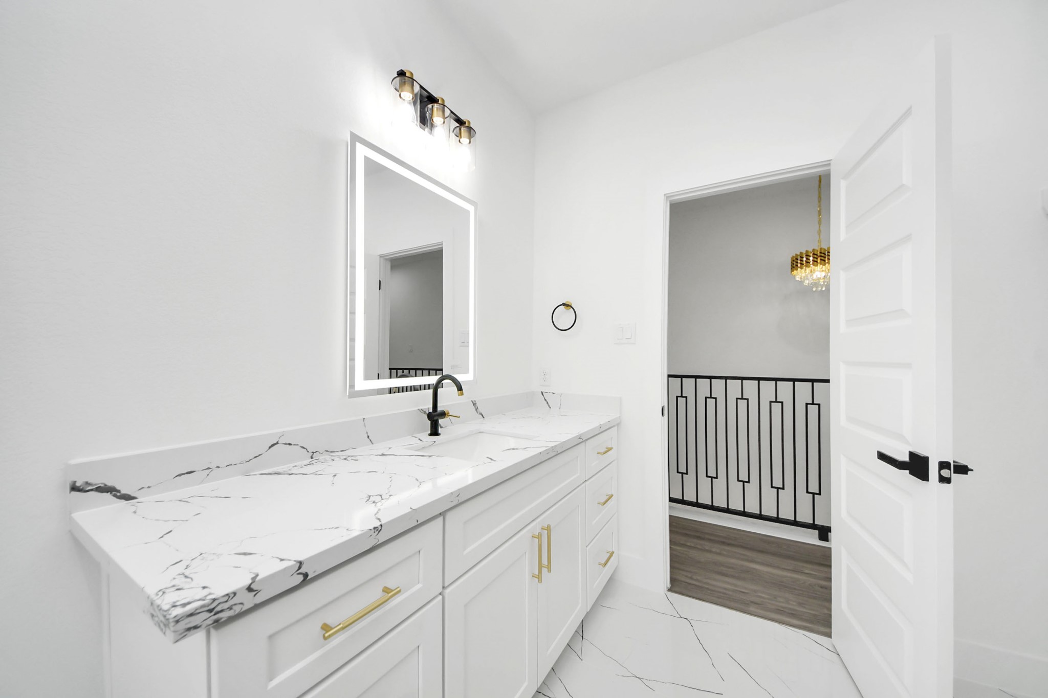 Elegant bathroom with a sleek marble countertop, modern fixtures, and a chic lighted mirror, offering a luxurious and contemporary feel.