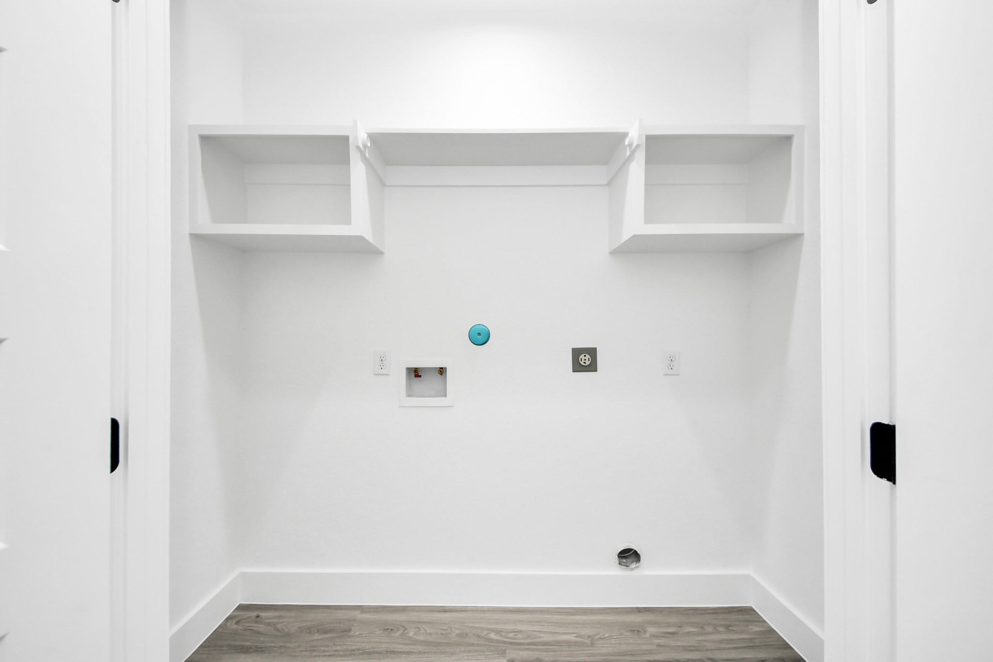 A spacious, well-lit laundry area with built-in shelving and modern hookups, ready for your appliances.