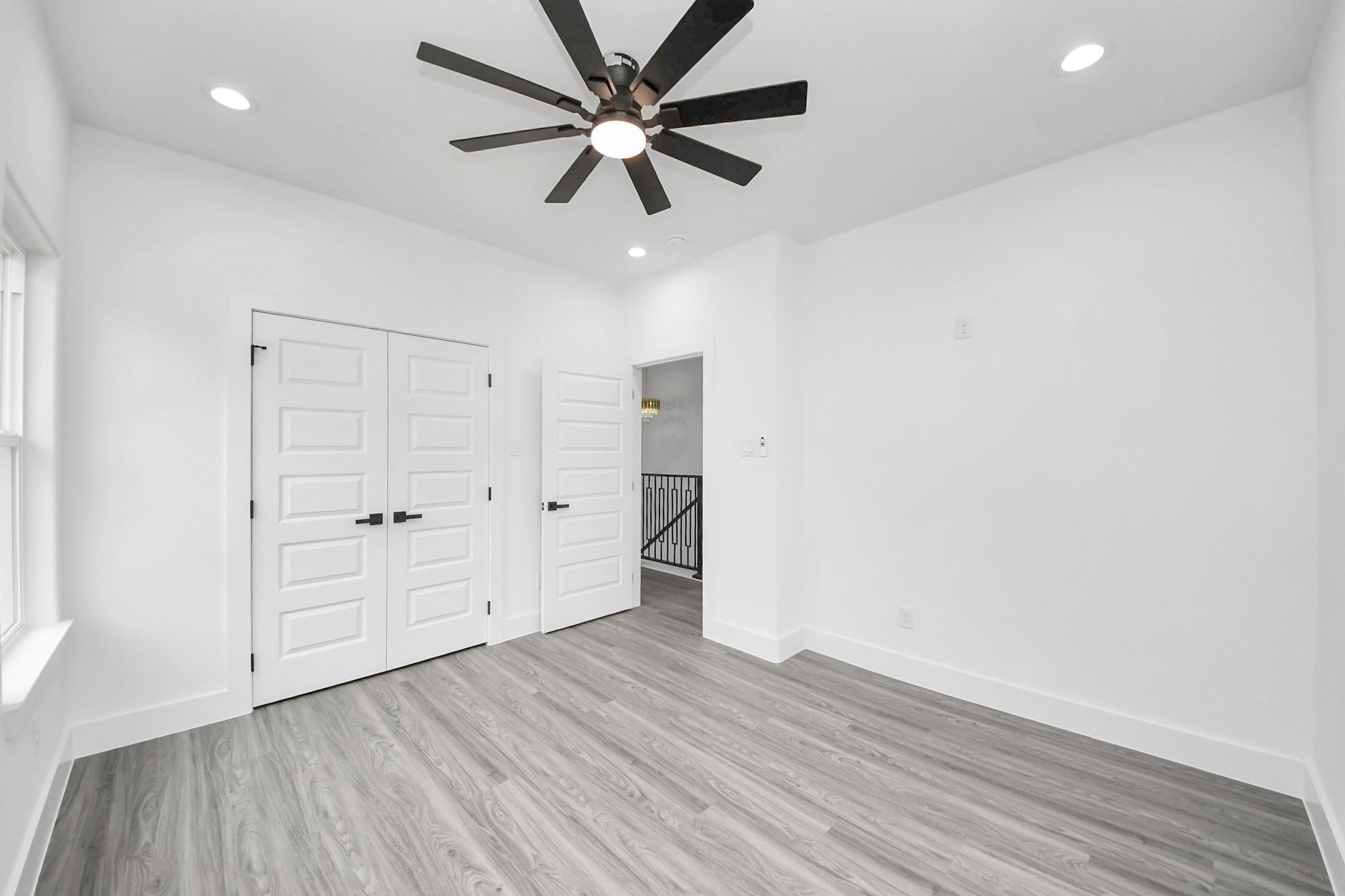 Bright and airy room featuring sleek wood flooring, modern recessed lighting, and a stylish ceiling fan, complemented by double doors for added charm.