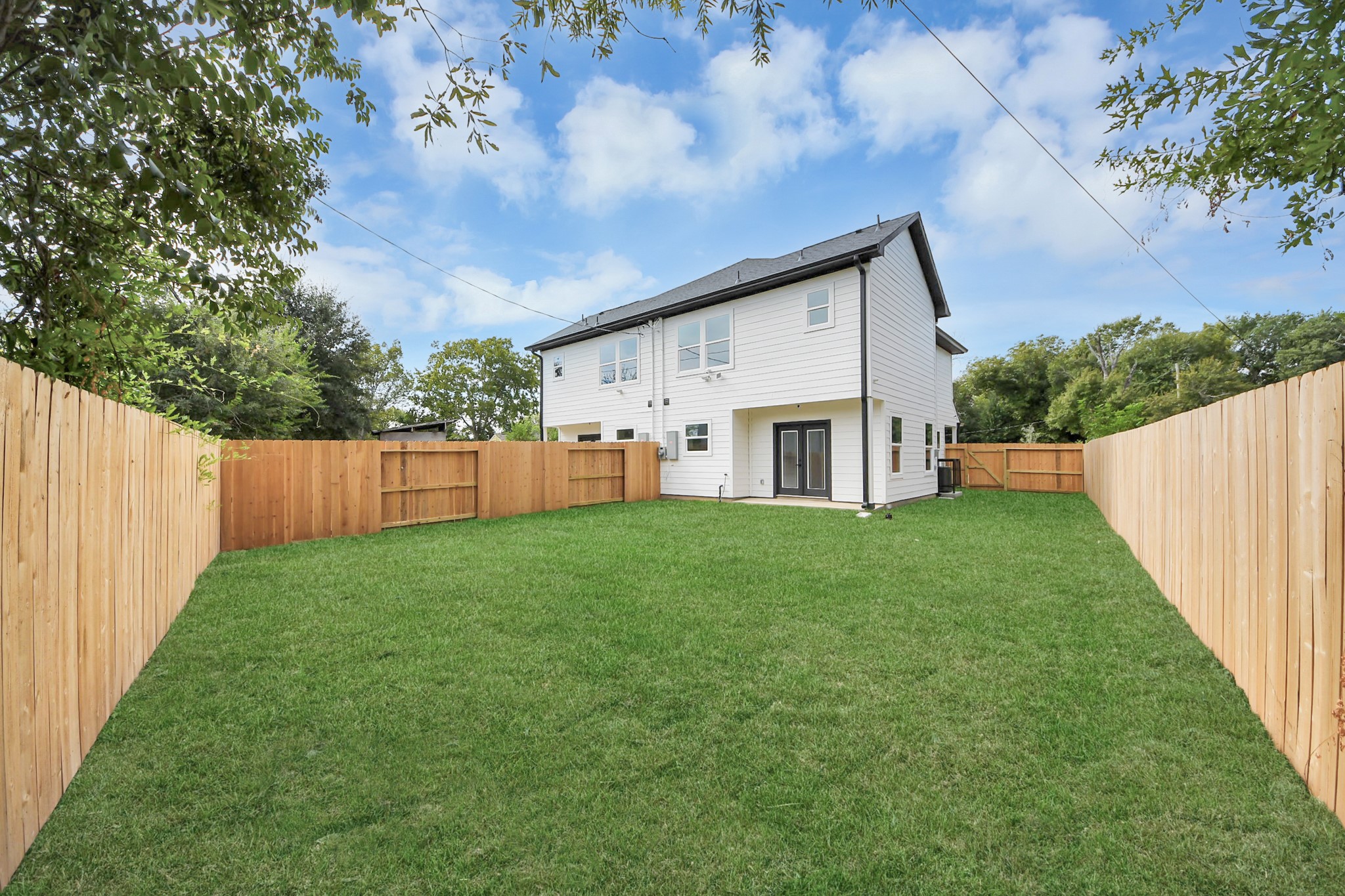 Spacious backyard with lush green lawn, enclosed by a wooden fence, ideal for outdoor activities and privacy.