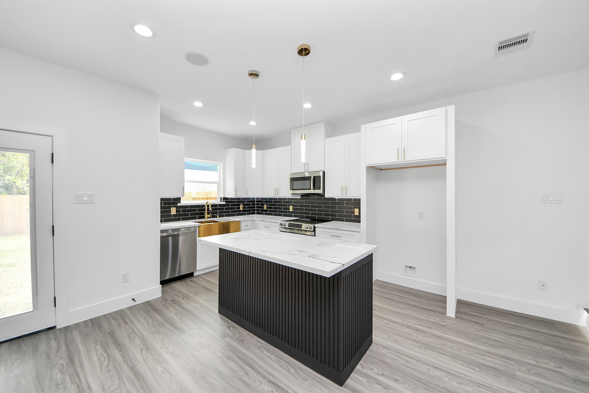 Sleek modern kitchen featuring a stylish black island with marble countertop, stainless steel appliances, and elegant black subway tile backsplash.