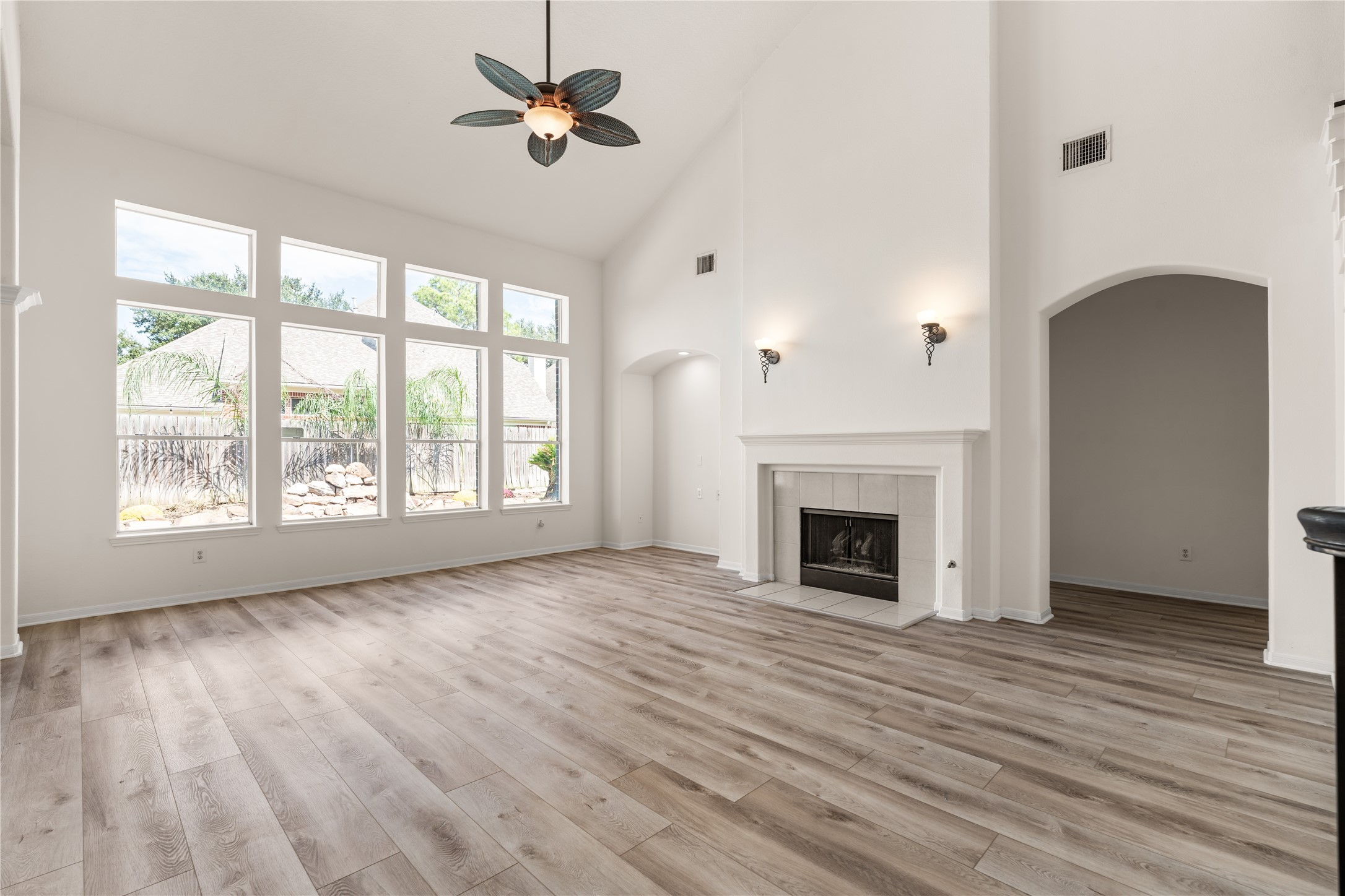 Open concept layout living area with fireplace, high ceilings, and natural light.