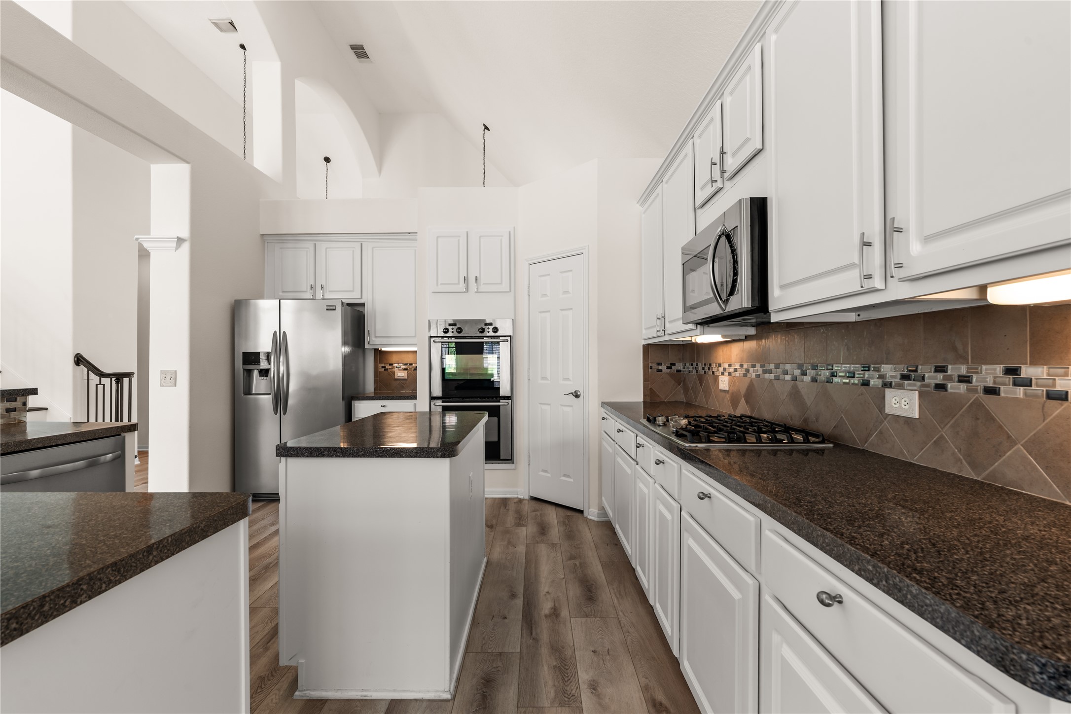 Gourmet kitchen with large island & stainless steel appliances.