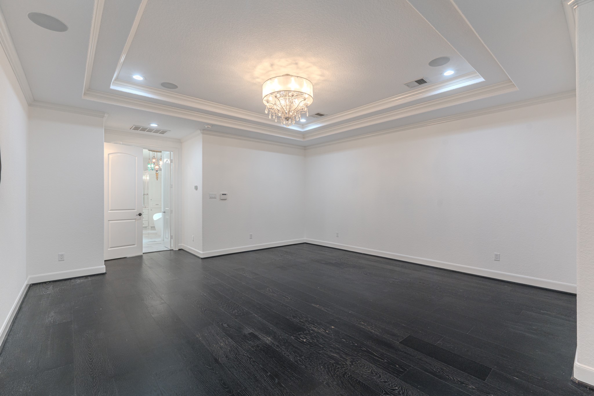 Massive Primary Bedroom with sitting area niche. Wood Floors, tray ceilings with crown molding detail. Speakers throughout.