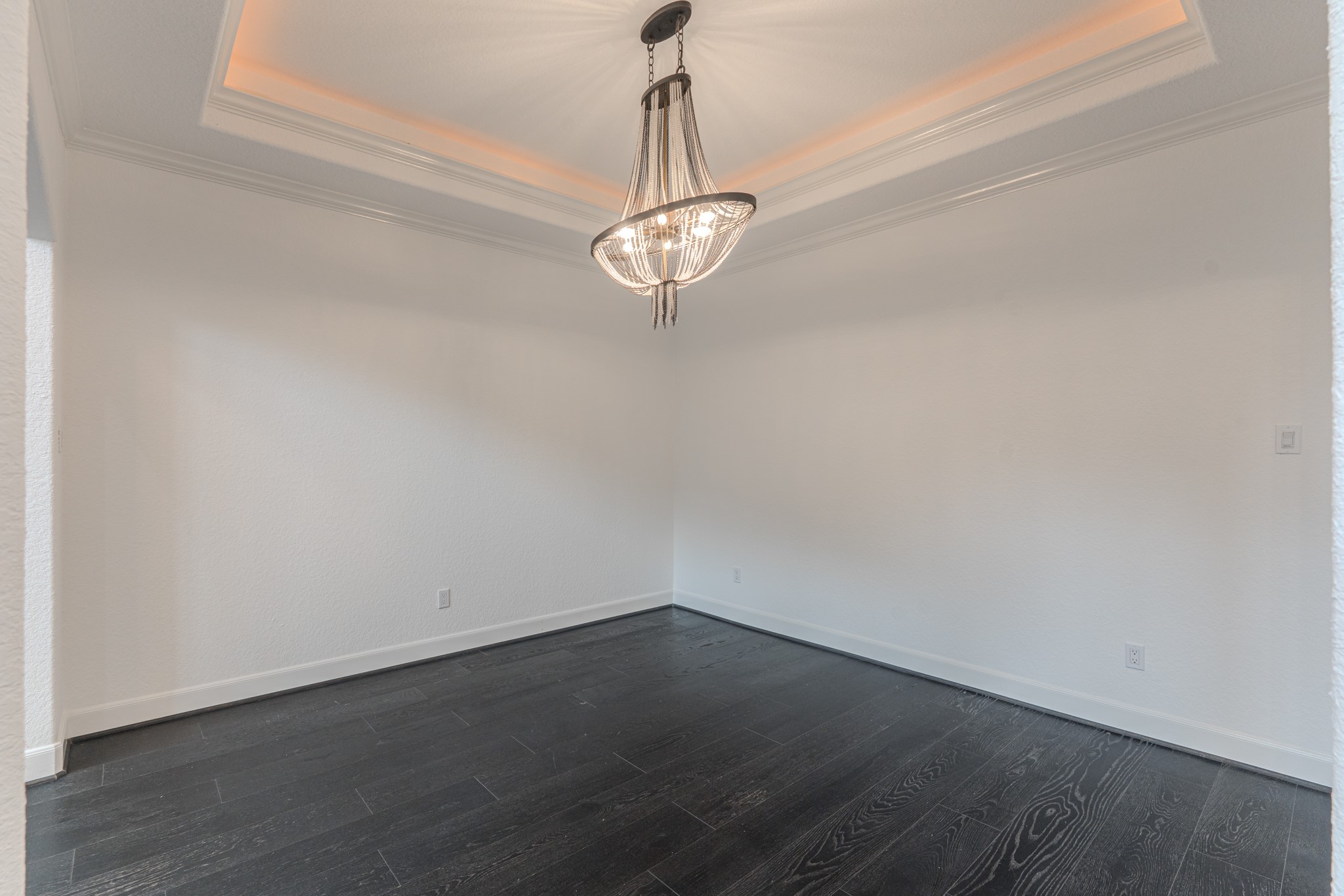 A elegant formal living room to host dinners. Chandelier is chic, crown molding, cove lighting, tray ceiling details and seamless engineered wood flooring.