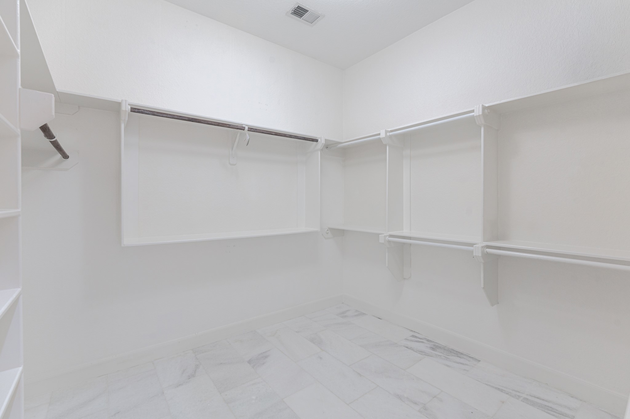 A dream walk-in closet as big as a room with marble flooring, built-ins.