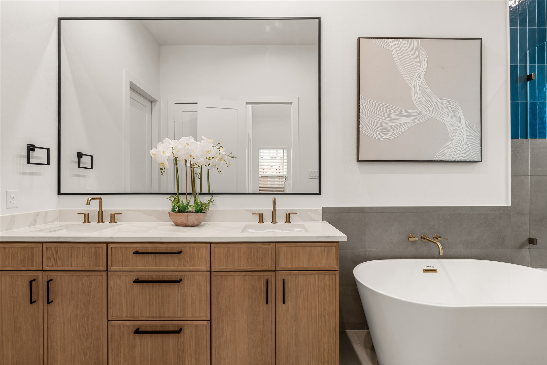 Dual undermount vanity area equipped with warm brass hardware and soft-close storage.