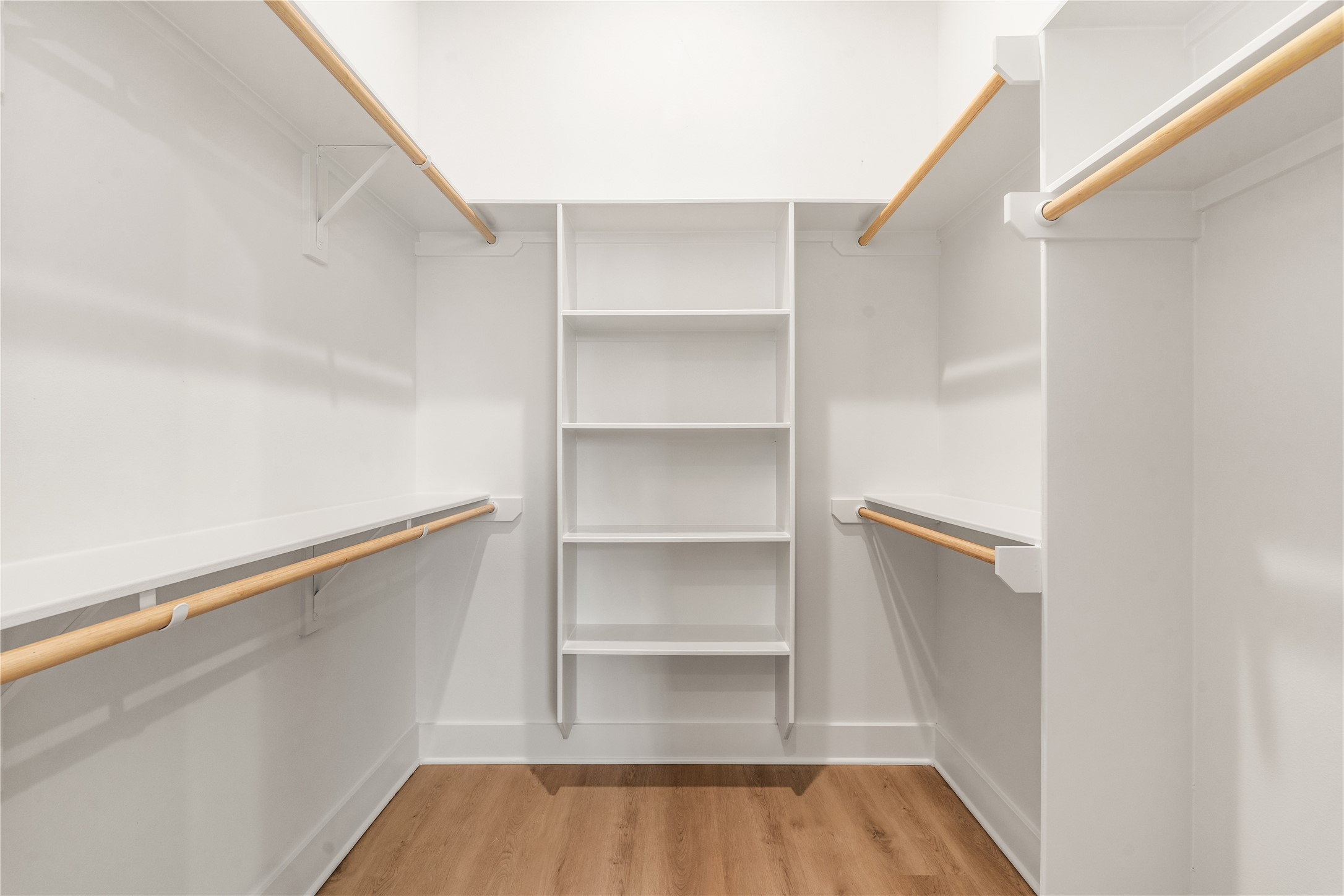 Custom walk-in primary closet featuring built-in shelving and dual hanging rods.