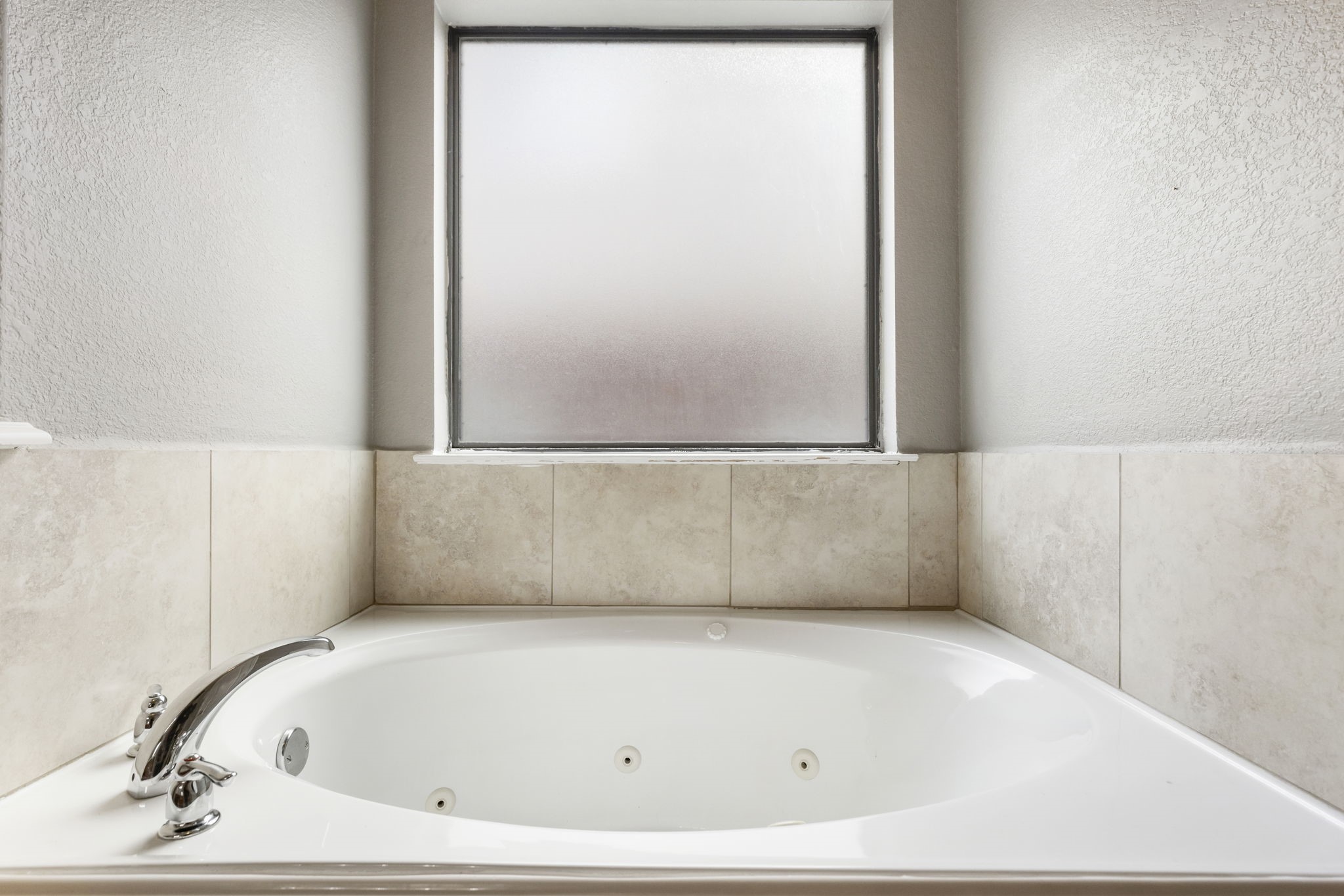 Luxuriate in the spacious primary bathroom featuring a serene jetted tub, perfect for relaxation.