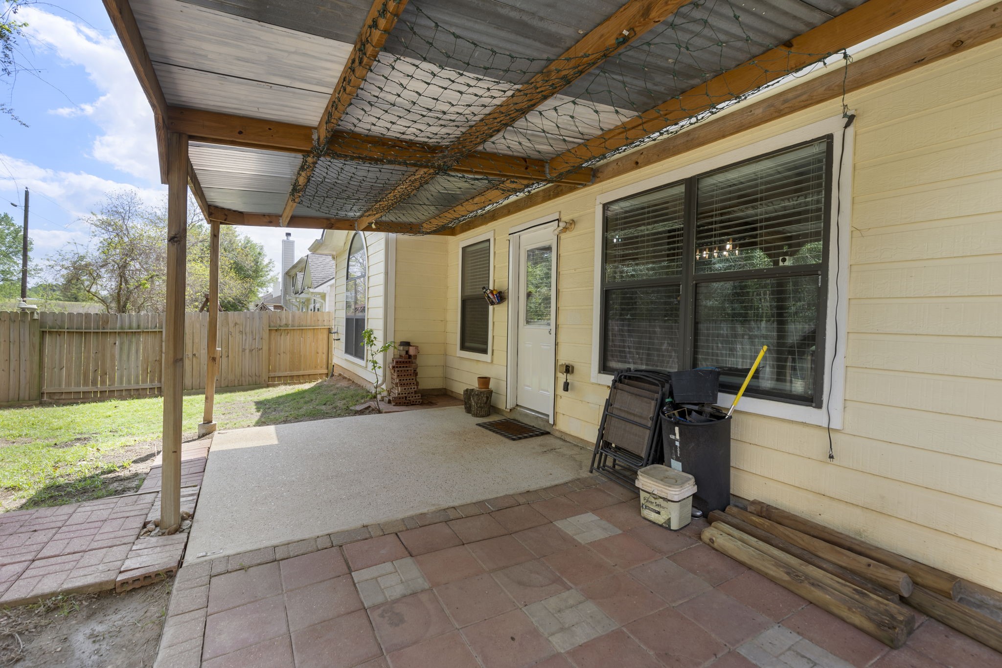 Charming covered patio area perfect for outdoor relaxation, featuring a sturdy wooden cover and access to a fenced backyard.