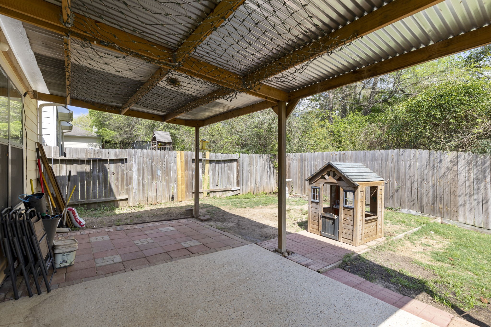 Charming backyard features a covered patio area perfect for relaxing and a delightful playhouse for children, all within a private fenced setting.