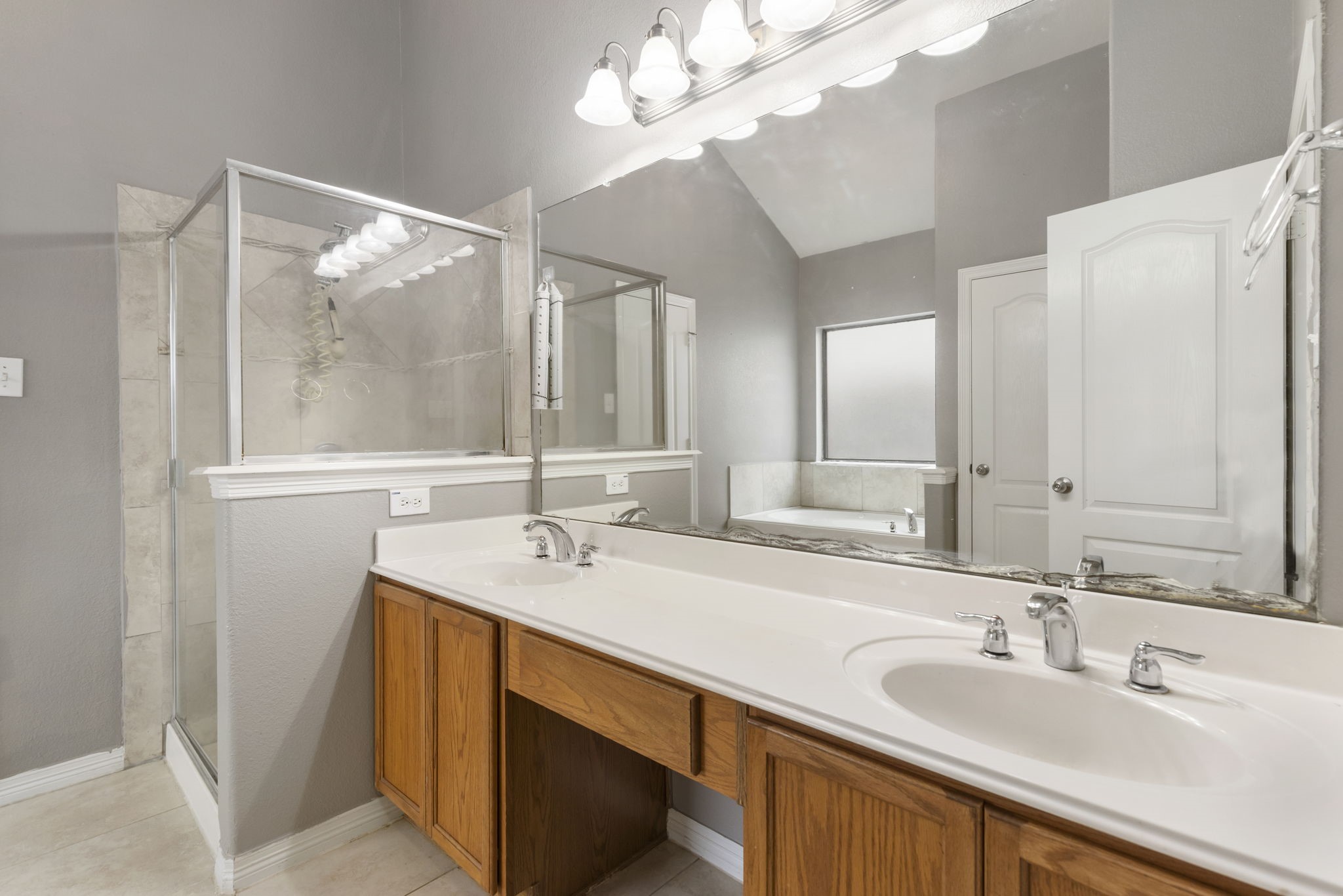 Luxurious primary bathroom featuring a spacious double vanity, elegant glass-enclosed shower, and a relaxing jetted tub for ultimate comfort.