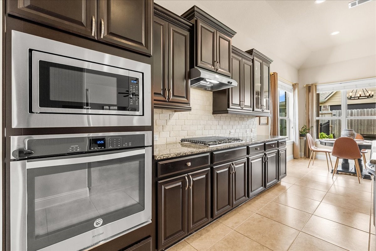 The chef-inspired kitchen with 42" cabinetry, crown molding, granite countertops, designer backsplash, stainless steel appliances, walk-in pantry, and butlers pantry.