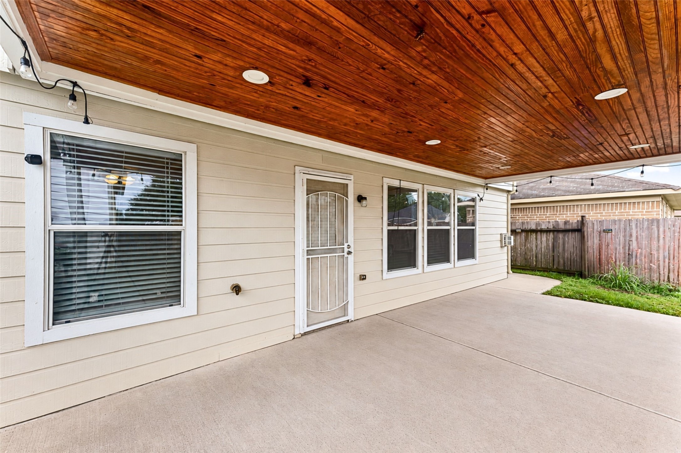 Spacious covered patio with wood-paneled ceiling is perfect for all outdoor activities.