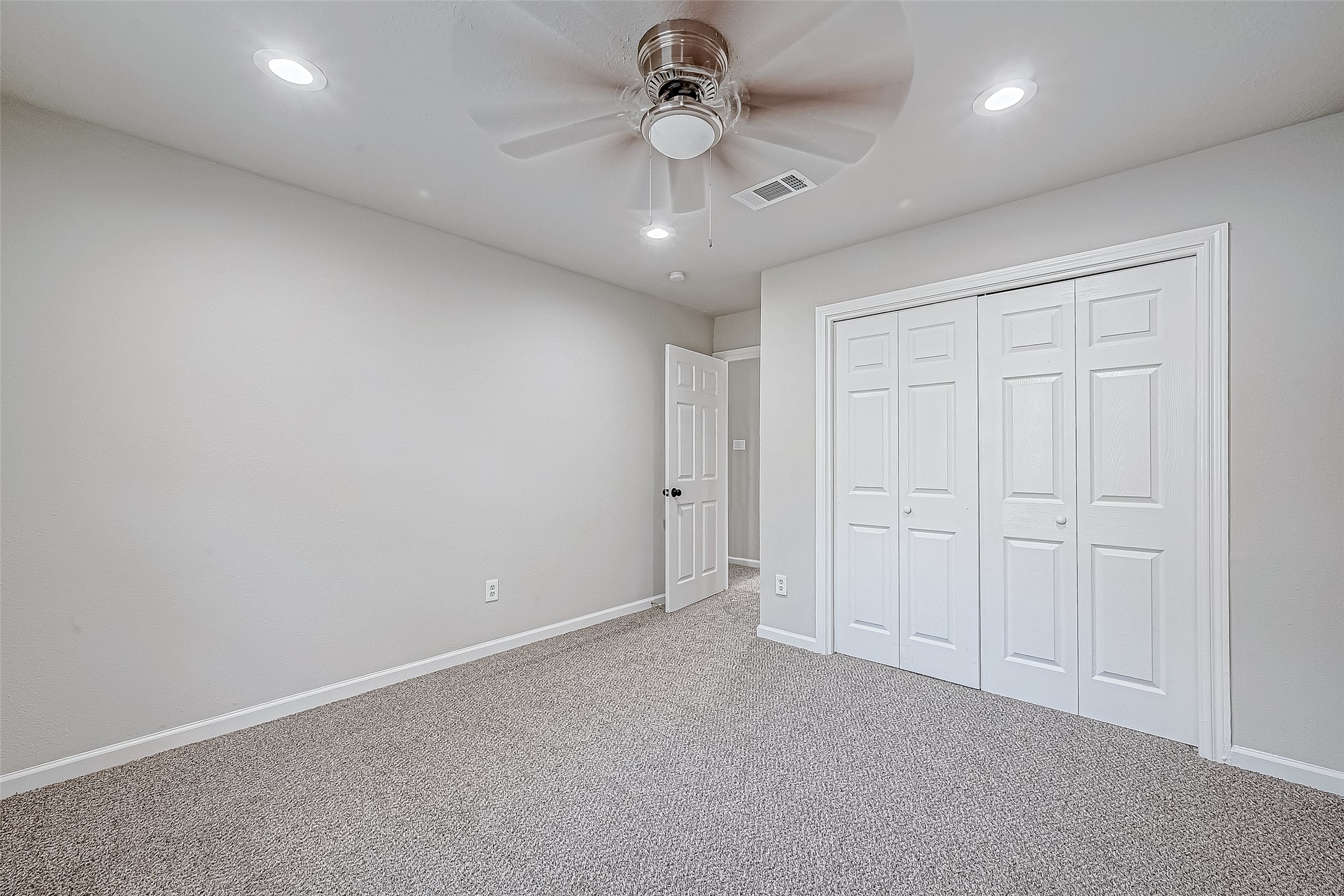 This bedroom has a ceiling fan and carpeted flooring. It features a double-door closet.