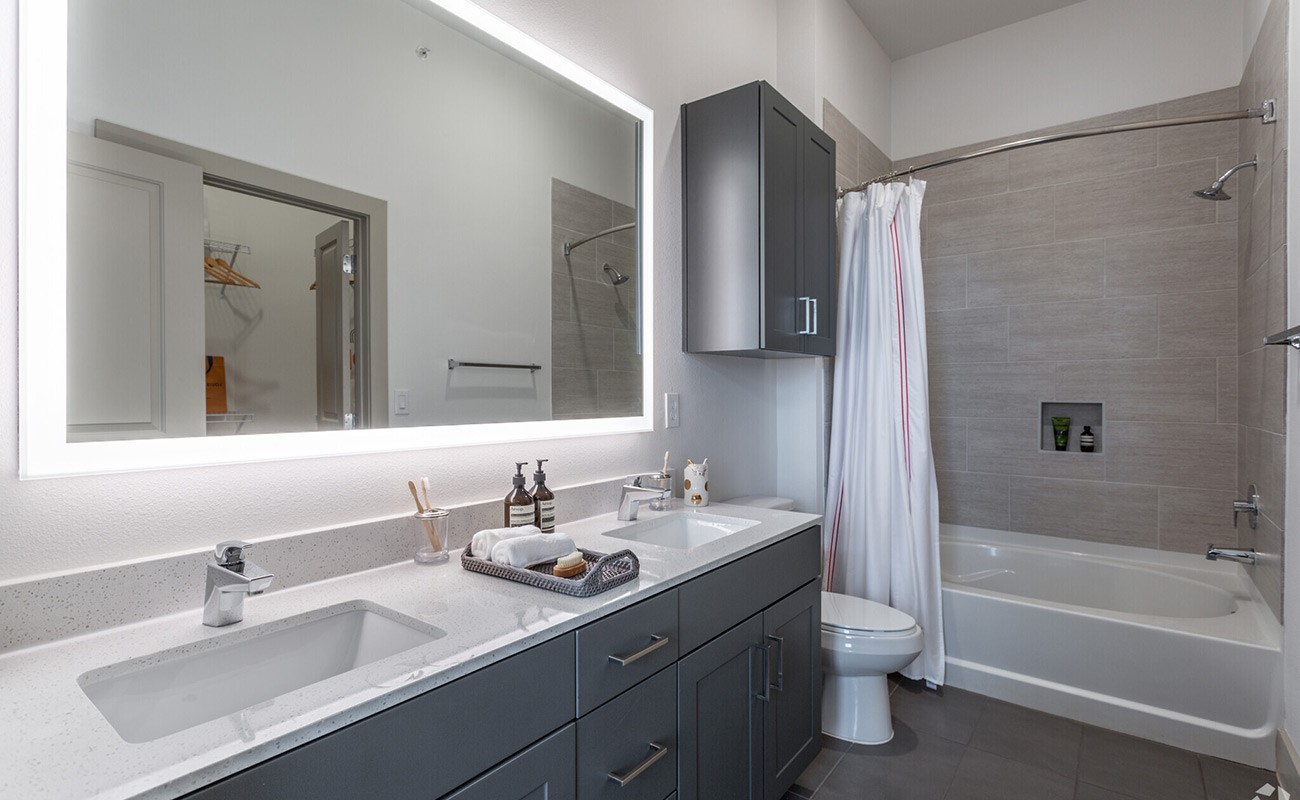 A beautiful balance of style and everyday comfort. Dual vanities, a spacious illuminated mirror, contemporary cabinetry, and a beautifully tiled bath surround bring a touch of understated luxury to your daily routine. *Pictures are from a similar unit, finishes and distribution may change.