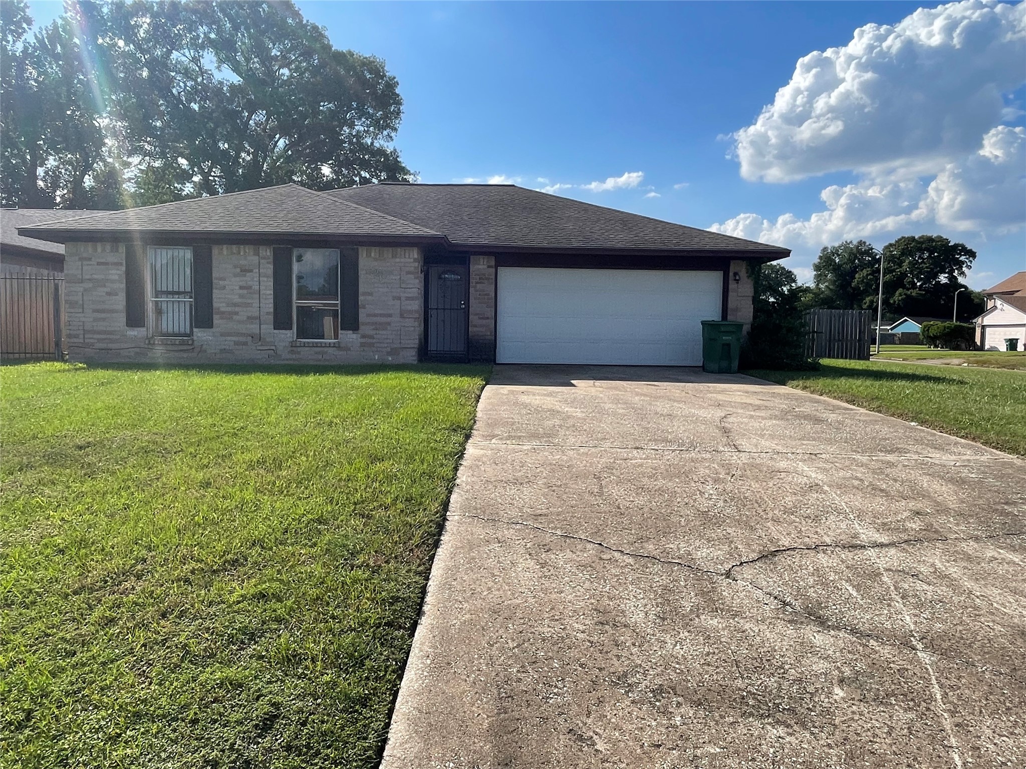 Front exterior view showcasing the single-story brick home with a two-car attached garage, extended driveway, well-maintained front lawn, and covered entryway.