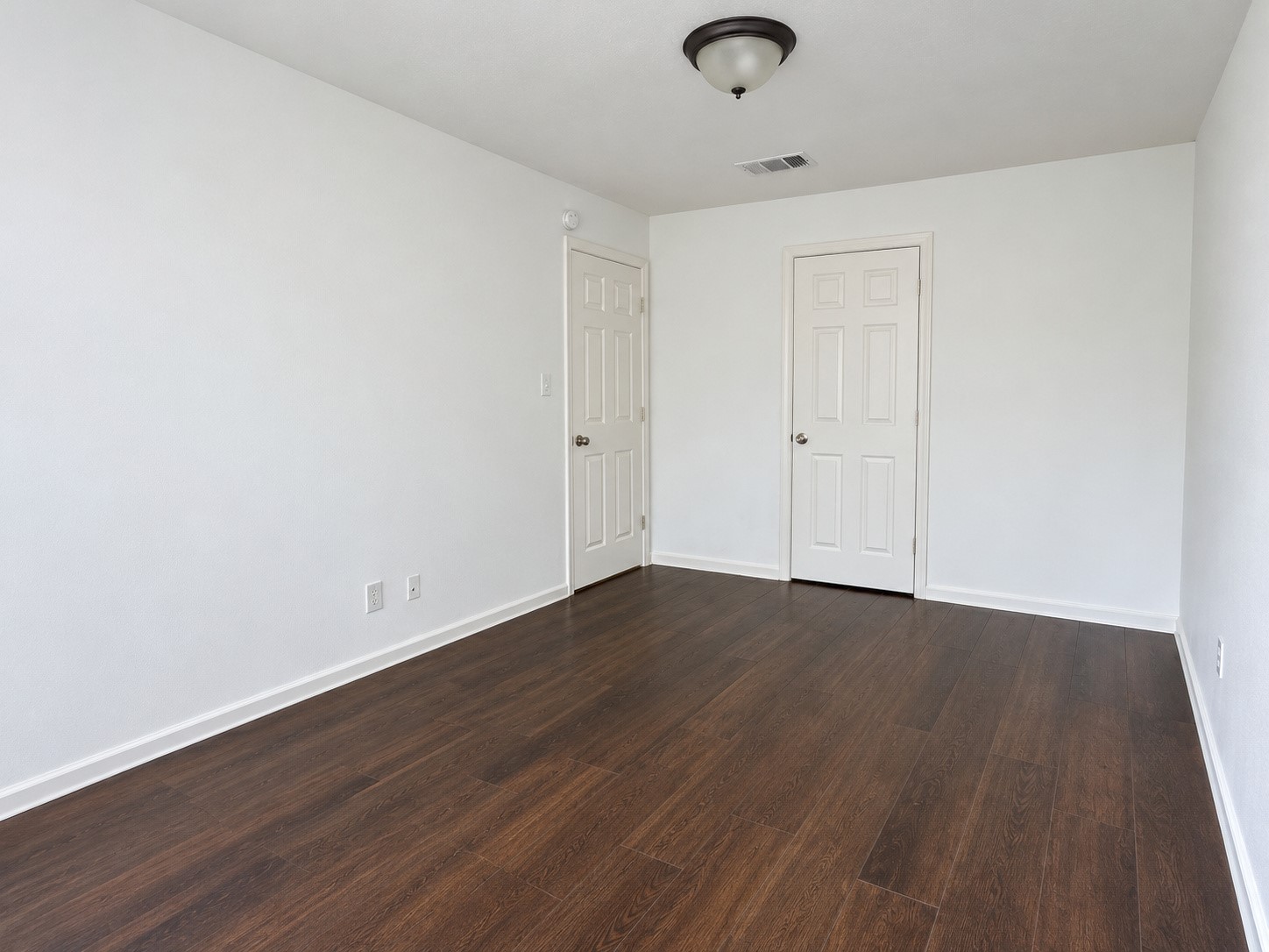 Third party highlights the rich, dark wood-look flooring, neutral walls, and spacious layout, offering flexibility for bedroom furnishings, a home office, or a guest room.