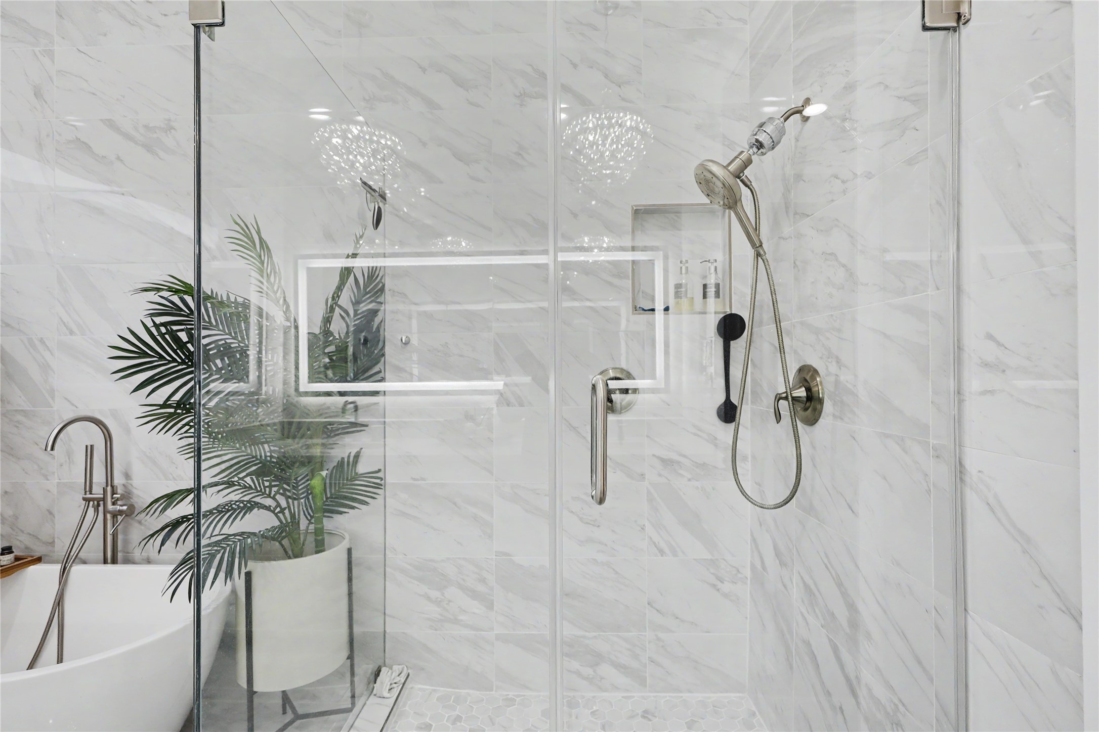 Large, frameless walk-in shower with marble tile from floor to ceiling.