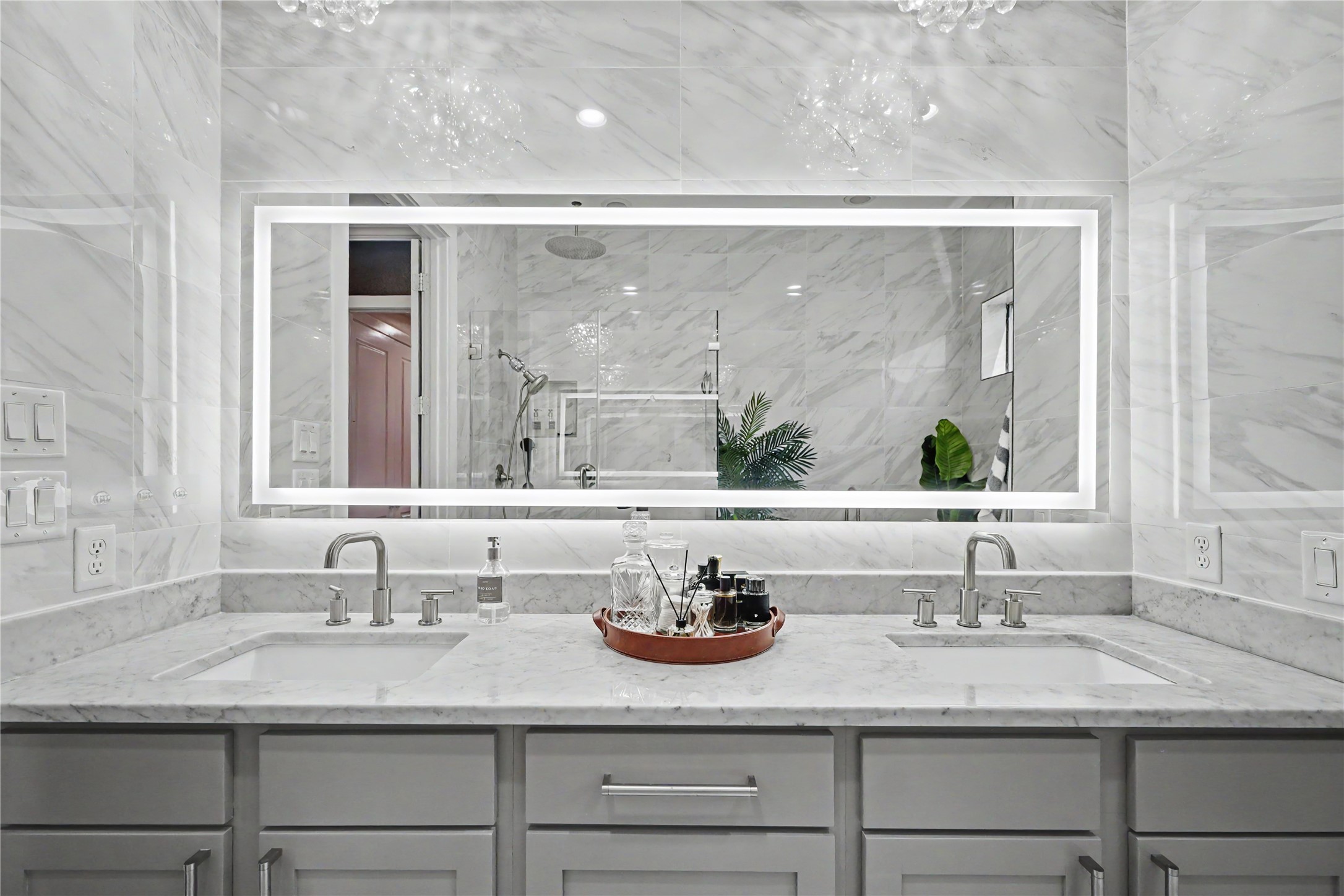 Incredible lighted-mirror and dual vanities in this primary bathroom.
