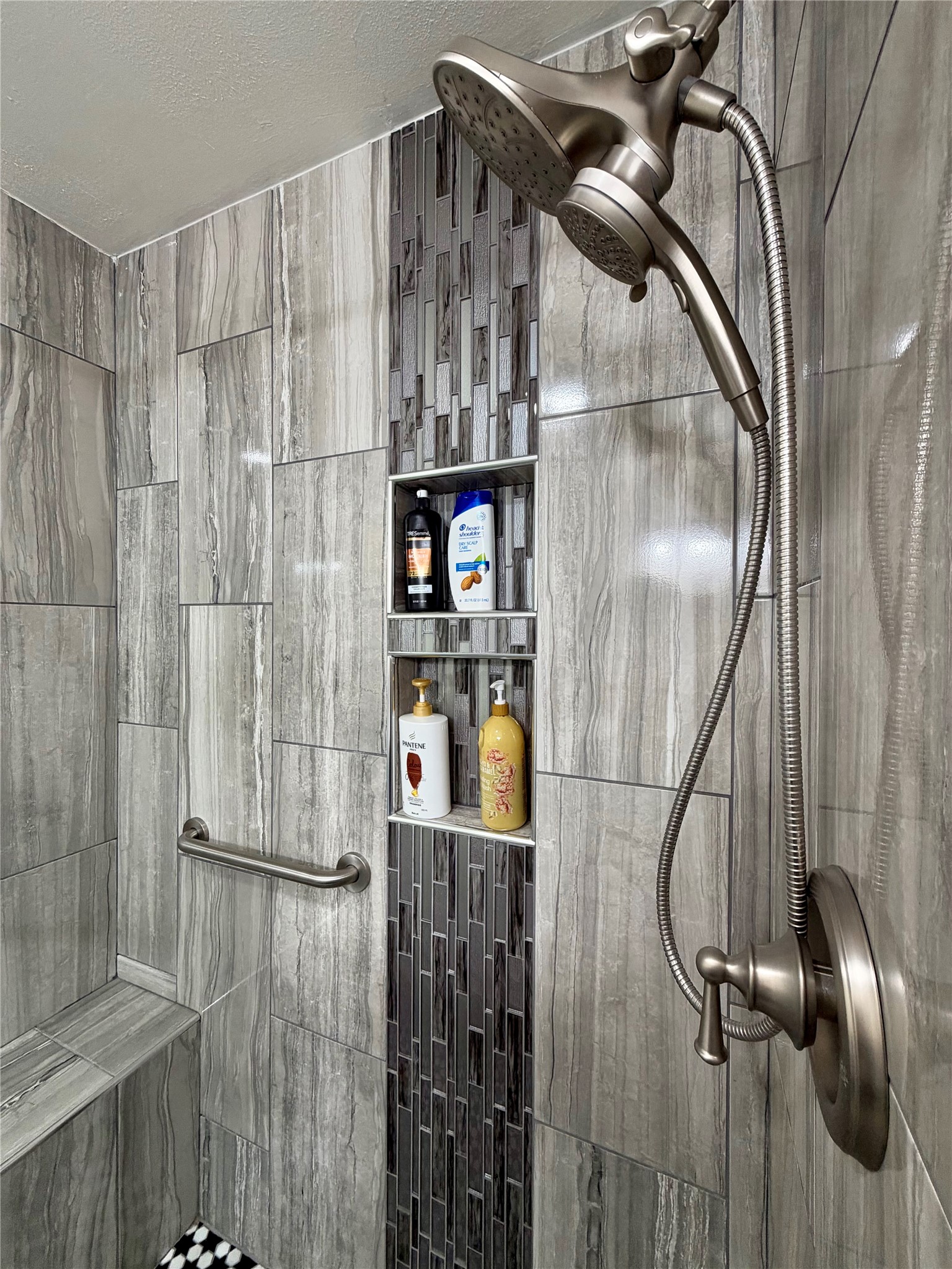 Custom tiled shower with bench, brushed nickel hardware and double shampoo cubbies