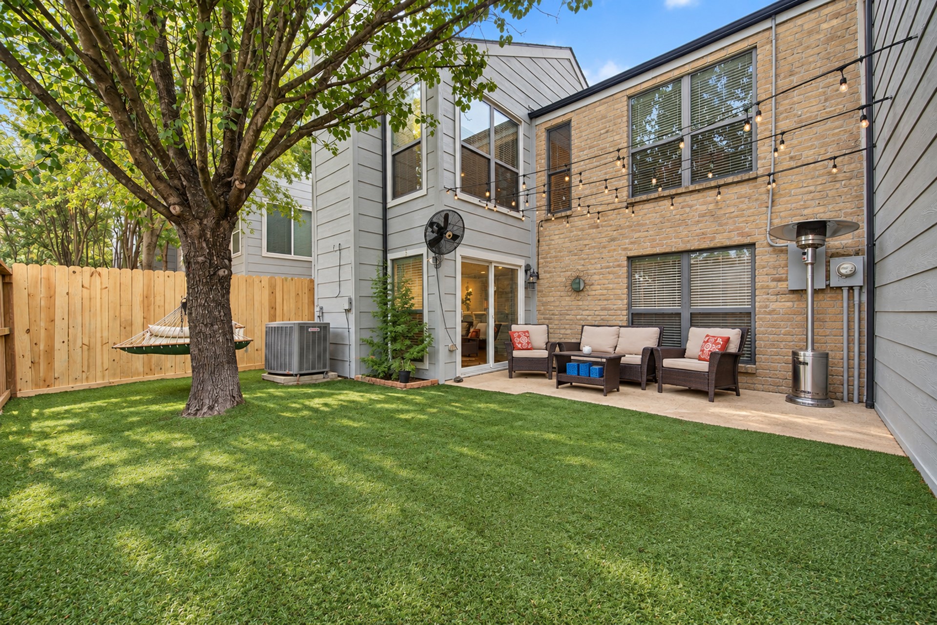 Fenced backyard with shade tree and inviting patio.