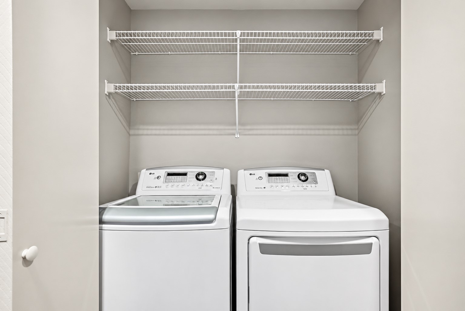 Convenient laundry area with overhead storage shelving.