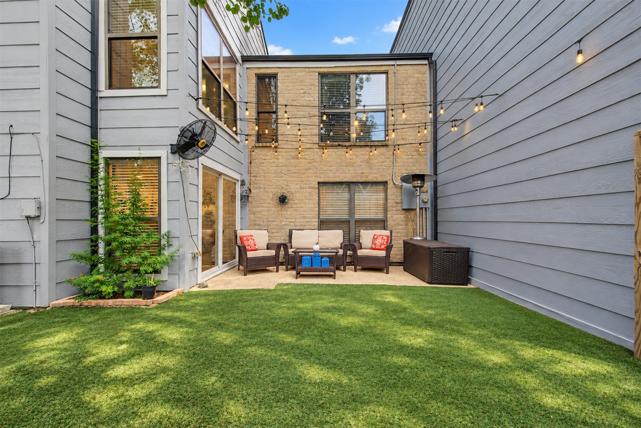 Private courtyard with patio seating and decorative string lighting.