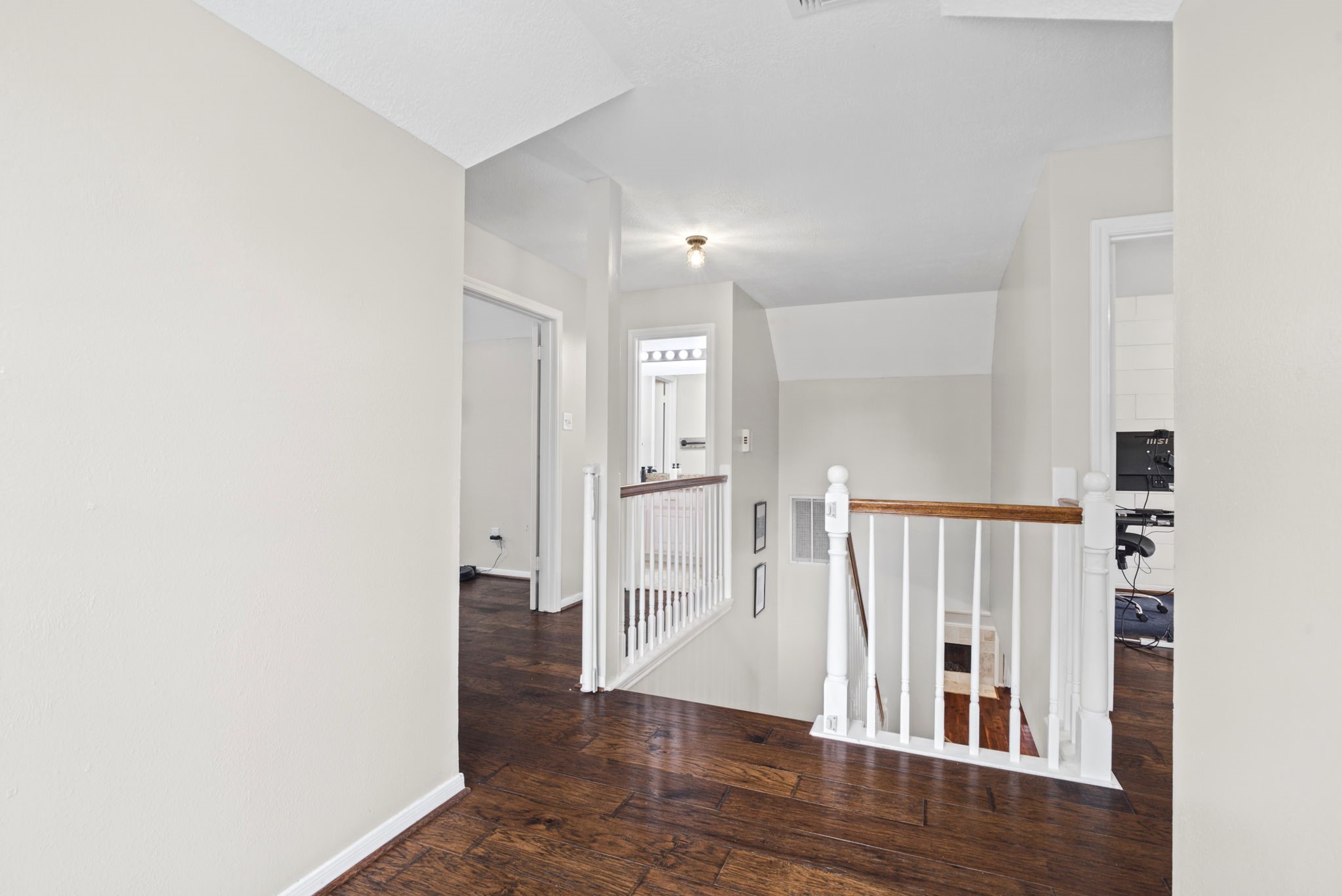 Beautiful engineered hardwood flooring that continues onto the staircase, complemented by a classic white railing. The cohesive design creates a bright, open, and inviting feel throughout the upstairs living space.