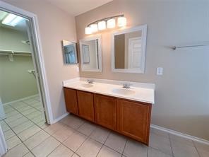Primary bathroom has double vanity, bright lighting and mirros