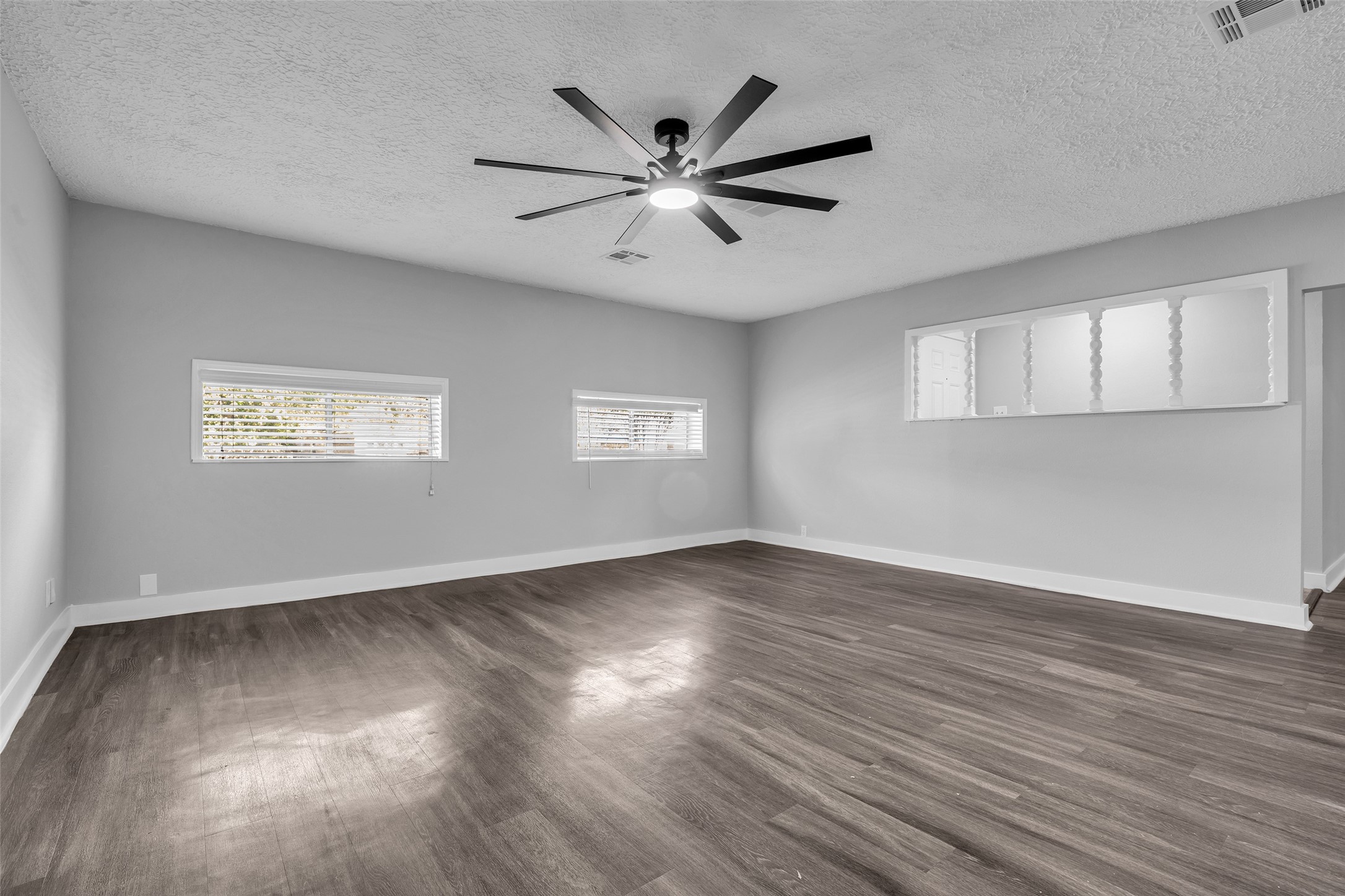Room to spread out, with natural light from two windows and wood-look plank flooring.