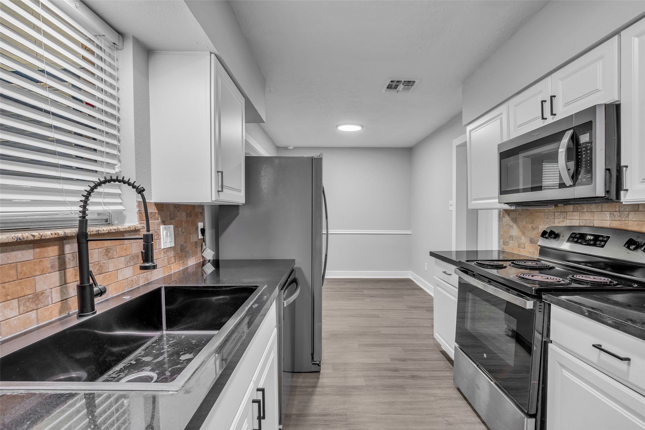 Rinse and prep at the stainless sink with a black pull-down faucet, with the dishwasher right beside it.