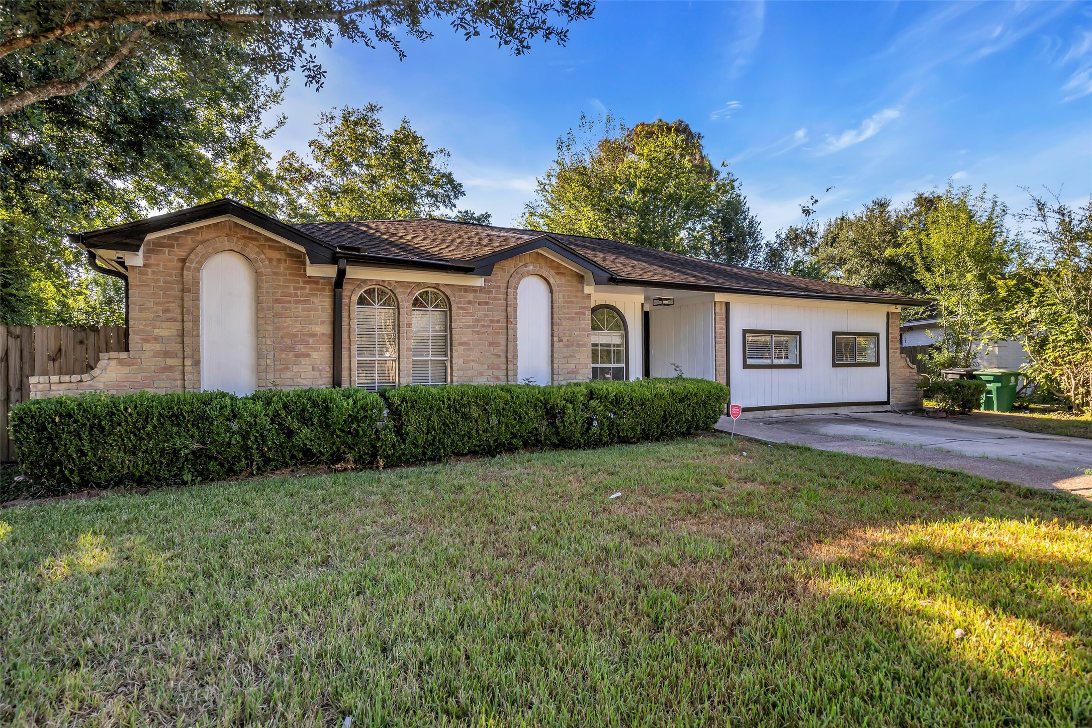 Mature shade trees and a broad lawn frame this single-story home, with a double-wide driveway for easy parking.
