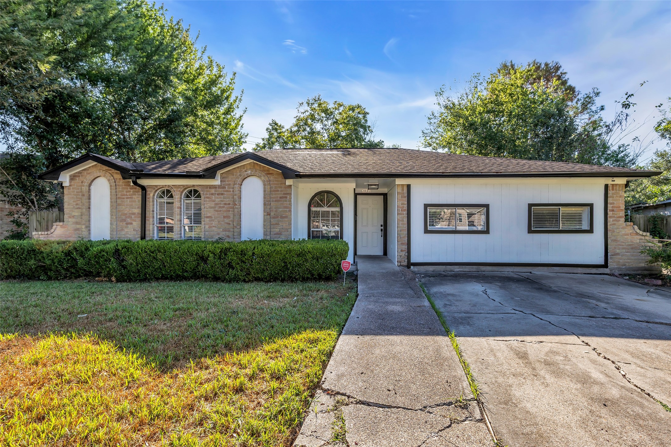 Welcome to 12331 Flushing Meadows Dr, a 3 bedroom, 2 bathroom home in Houston. Curb appeal starts here: a single-story brick home with arched windows, a manicured front hedge and a wide front lawn.