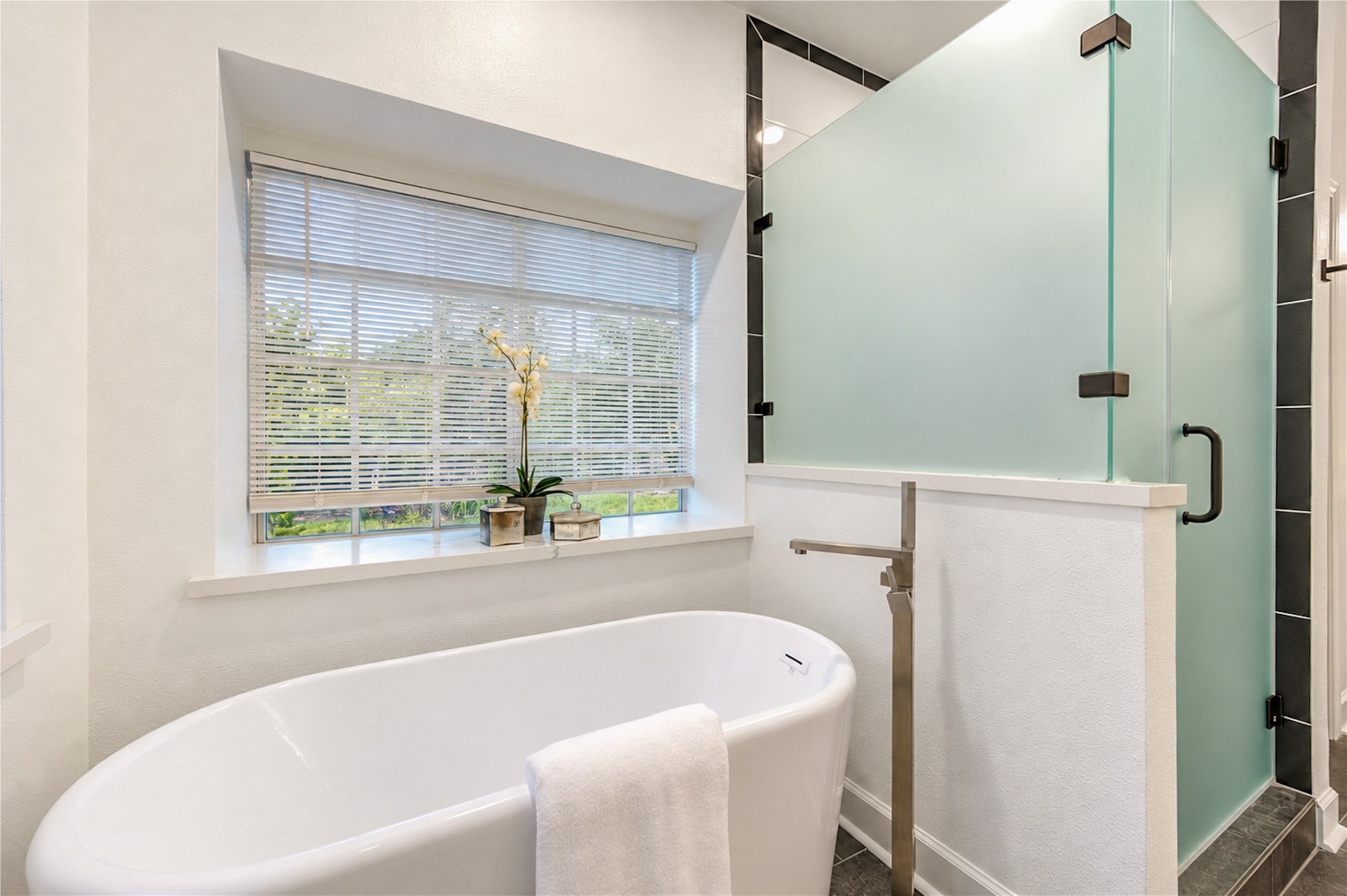 Your own spa-inspired escape awaits! Soak away the stresses of the day in the elegant freestanding tub or refresh in the spacious glass-enclosed walk-in shower. Beautiful natural light and peaceful views of the greenery outside create the perfect atmosphere for relaxation and everyday indulgence.