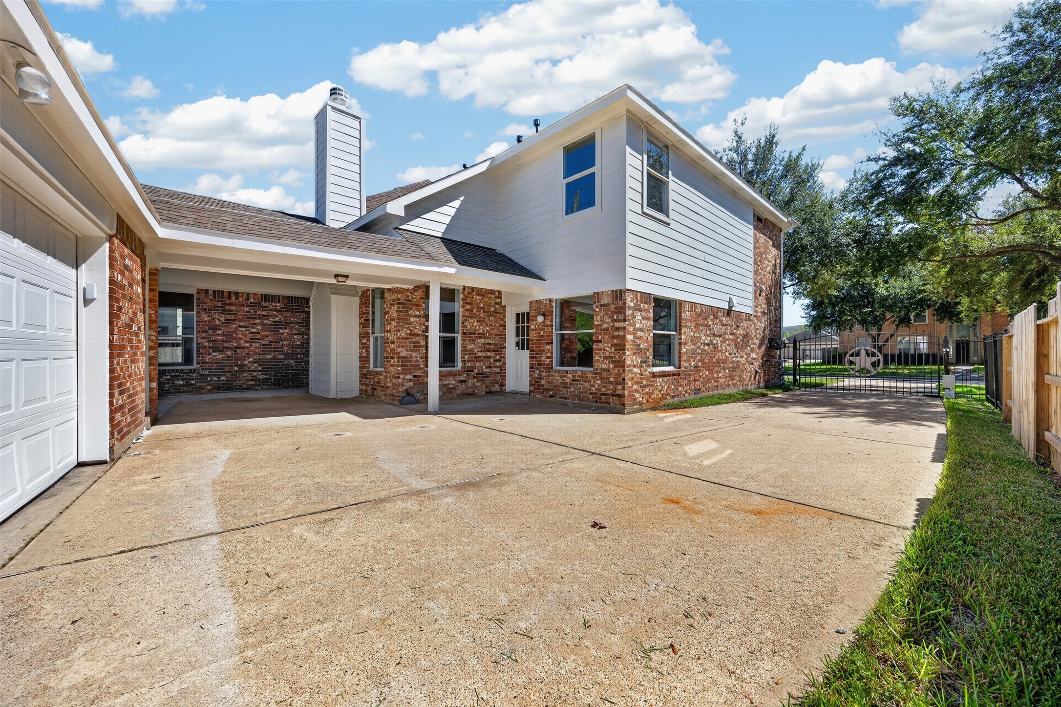 Spacious driveway featuring an automatic gate and a two-car garage, offering outdoor space for parking and activities.