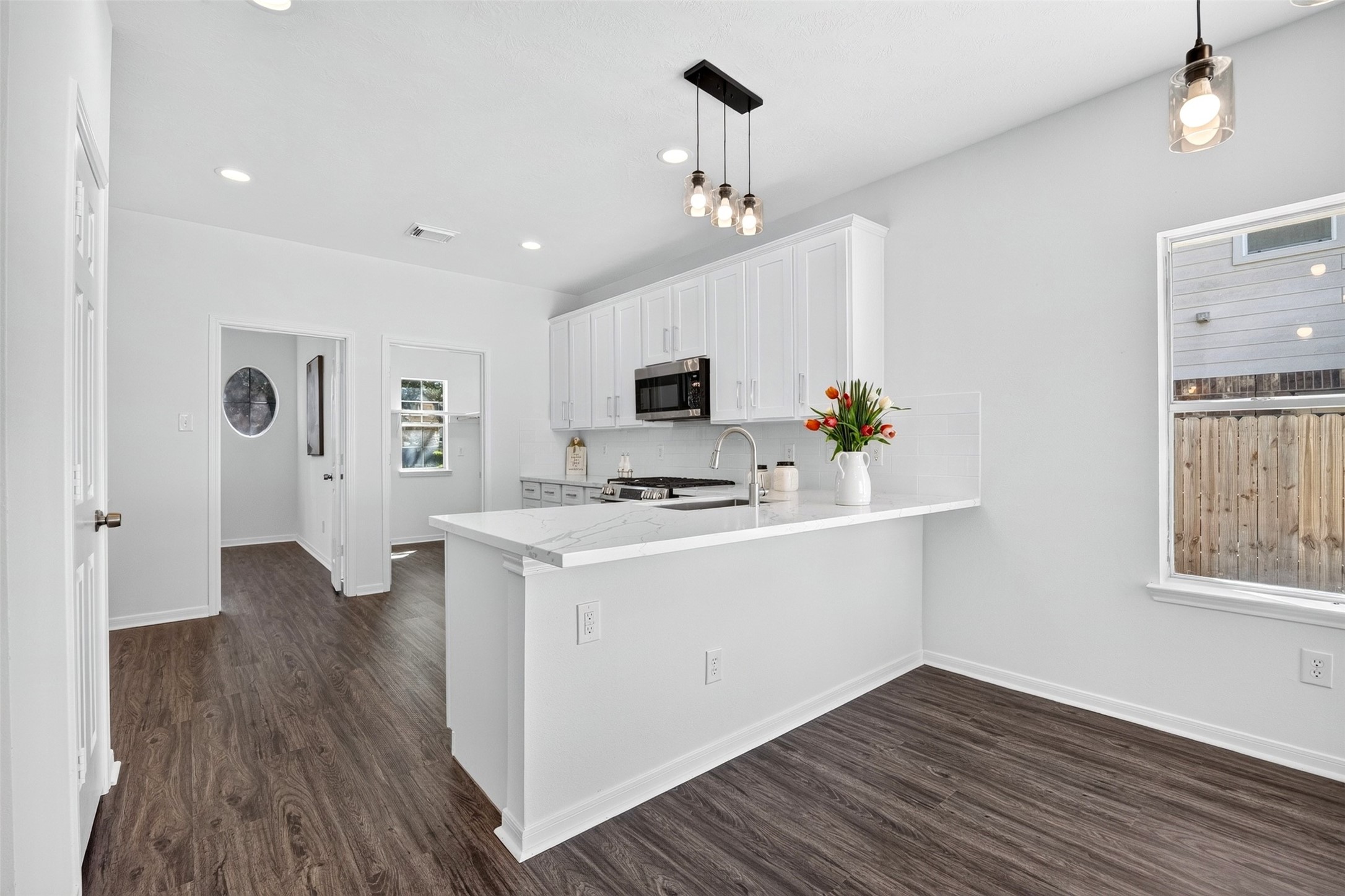 Bright, modern kitchen with sleek white cabinetry and elegant pendant lighting, offering a welcoming space for cooking and entertaining.