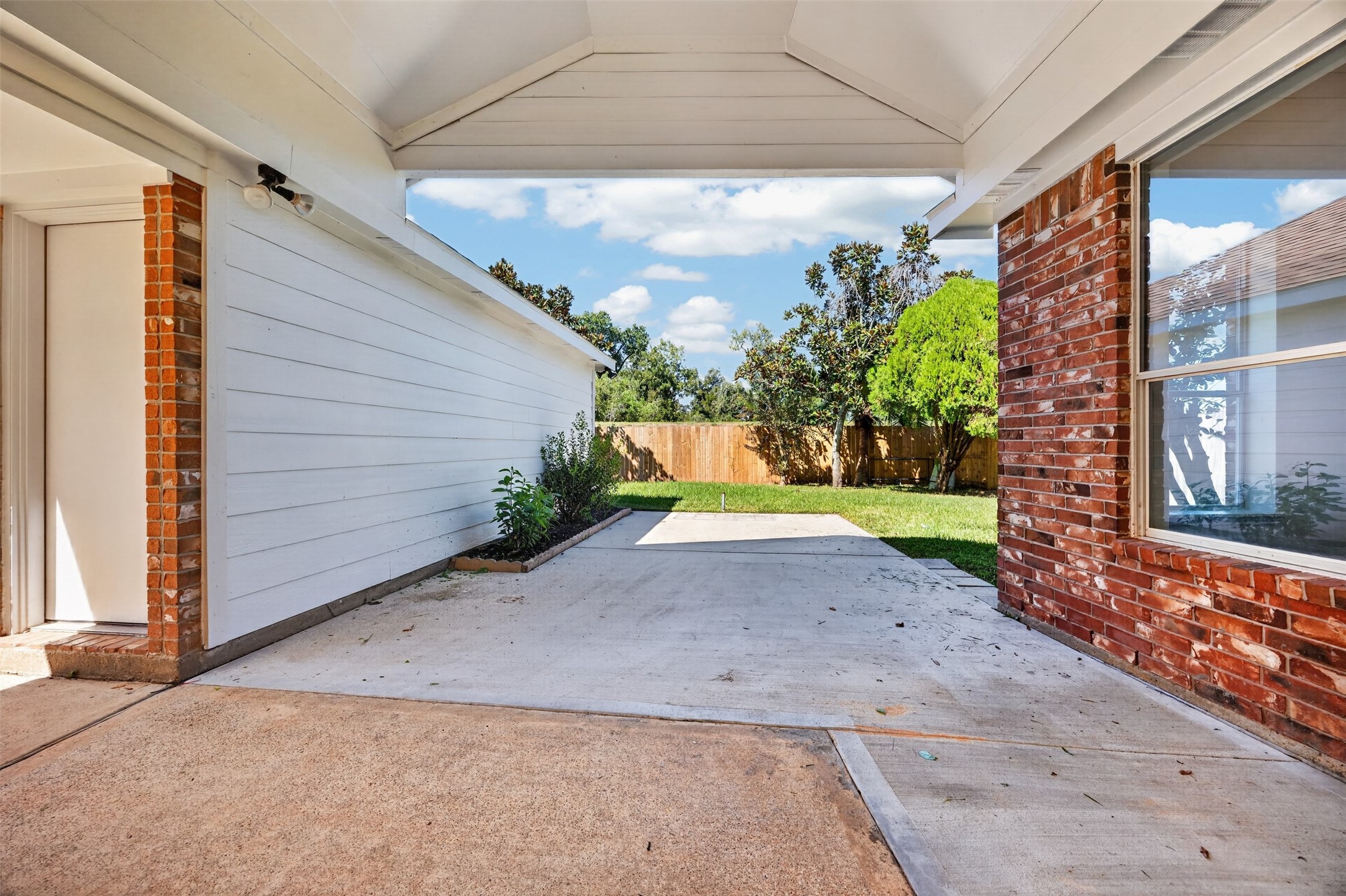 Spacious backyard patio, perfect for outdoor entertaining, complemented by a lush green lawn and privacy fencing.