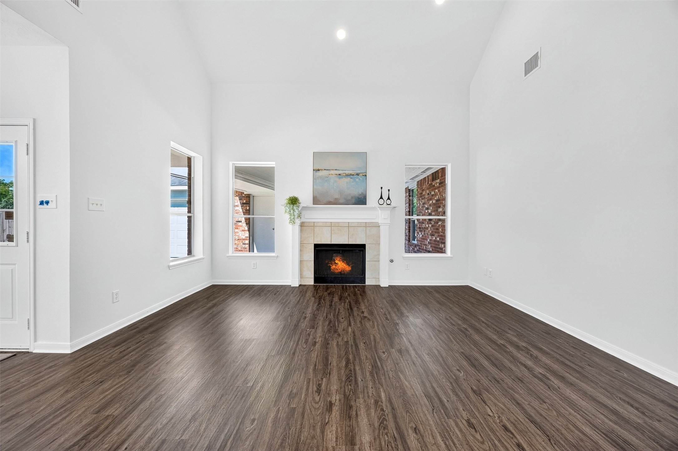 Spacious living room with high ceilings, a cozy fireplace, and 3 windows that provide abundant natural light.