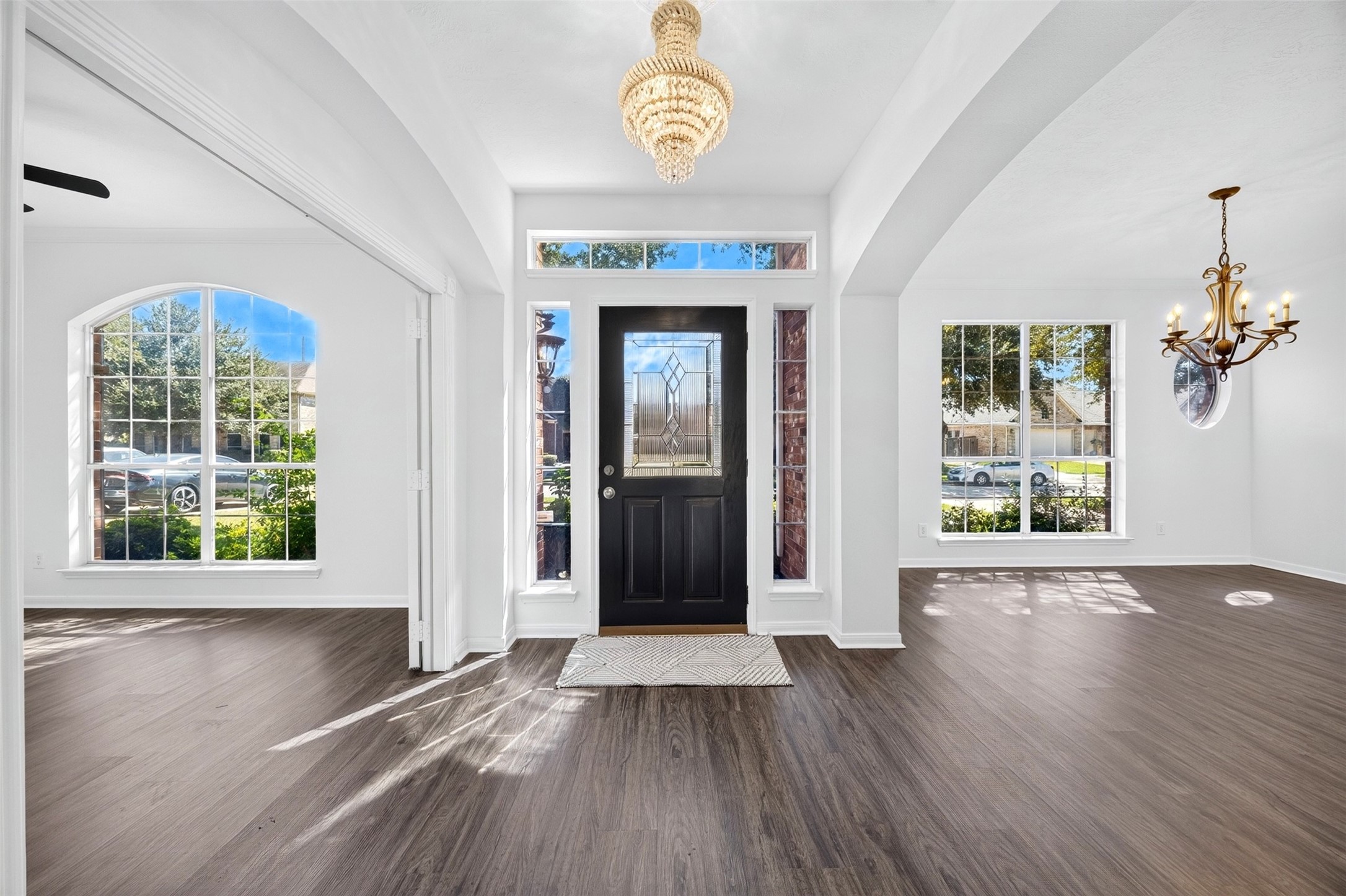 Bright and inviting entryway with luxury vinyl plank flooring, large windows for natural light, and a stylish chandelier accentuating the space.