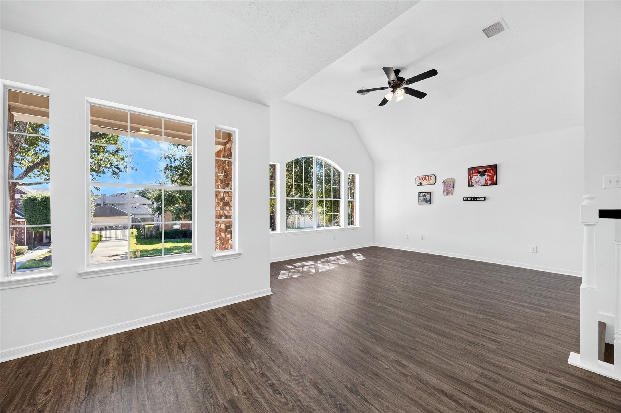 Bright and spacious game room area featuring large windows that provide abundant natural light and a stylish ceiling fan.