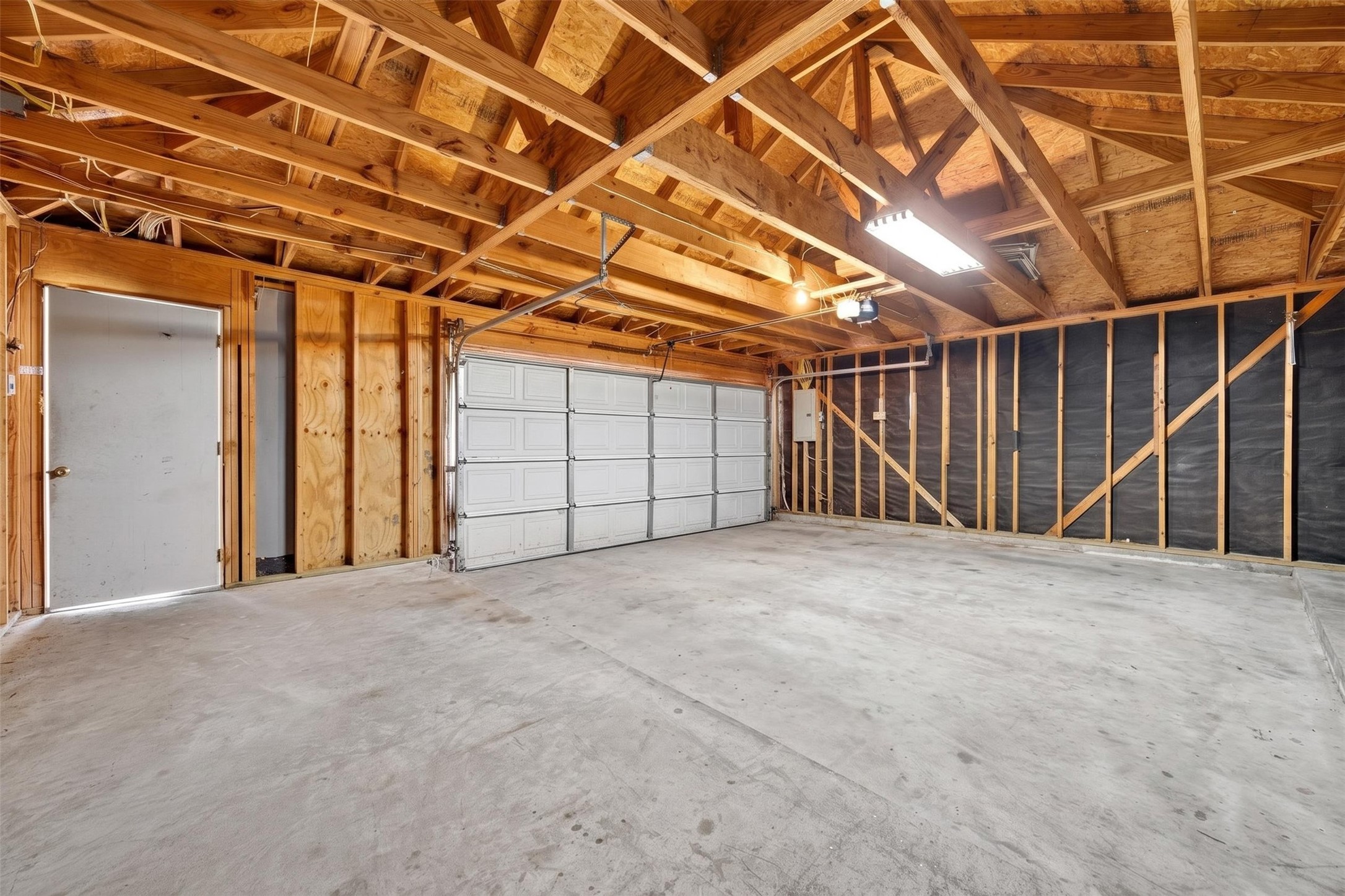 Spacious two-car garage with exposed beams and ample lighting, perfect for storage or a workshop.