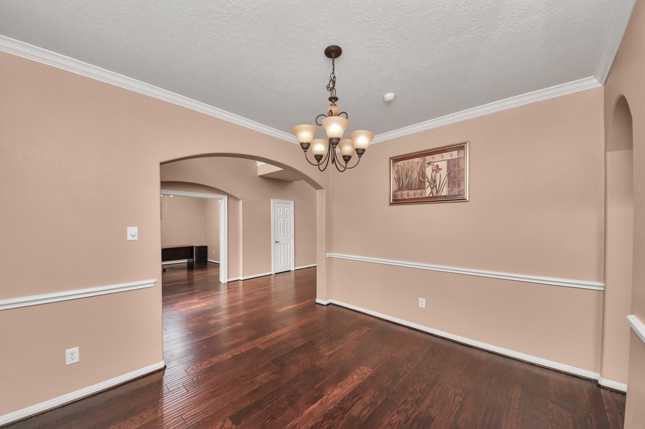 Elegant dining room with rich hardwood floors, crown molding, and a classic chandelier, offering a stylish setting for gatherings.