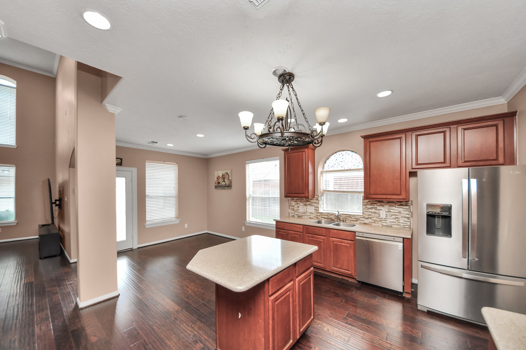 Spacious kitchen with elegant wood cabinetry, stainless steel appliances, and a stylish island, seamlessly opening to the living area with rich hardwood floors and abundant natural light.