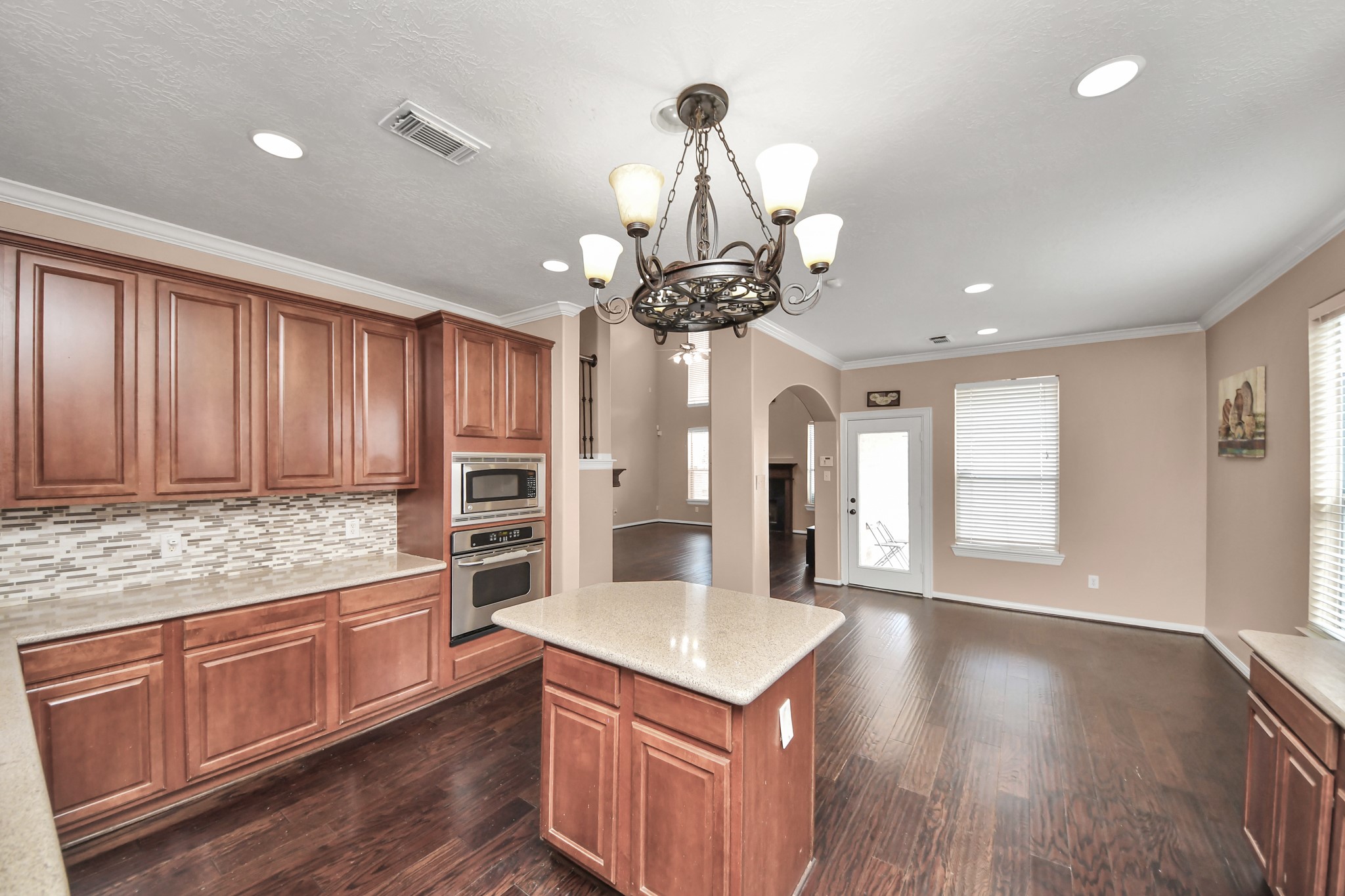 Spacious kitchen with elegant wood cabinetry, a central island, and modern built-in appliances, complemented by a stylish tile backsplash and a cozy breakfast area. Spacious kitchen with elegant wood cabinetry, a central island, and modern built-in appliances, complemented by a stylish tile backsplash and a cozy breakfast area.