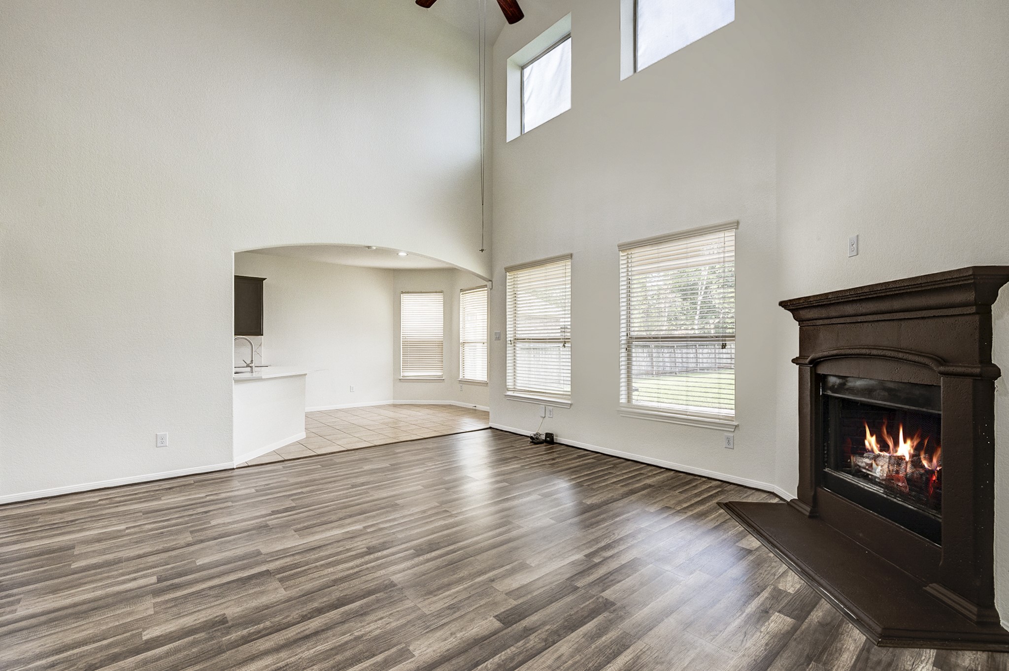 Spacious living area with high ceilings, elegant wood flooring, and a cozy fireplace, seamlessly connecting to a bright dining nook with large windows and an open kitchen.