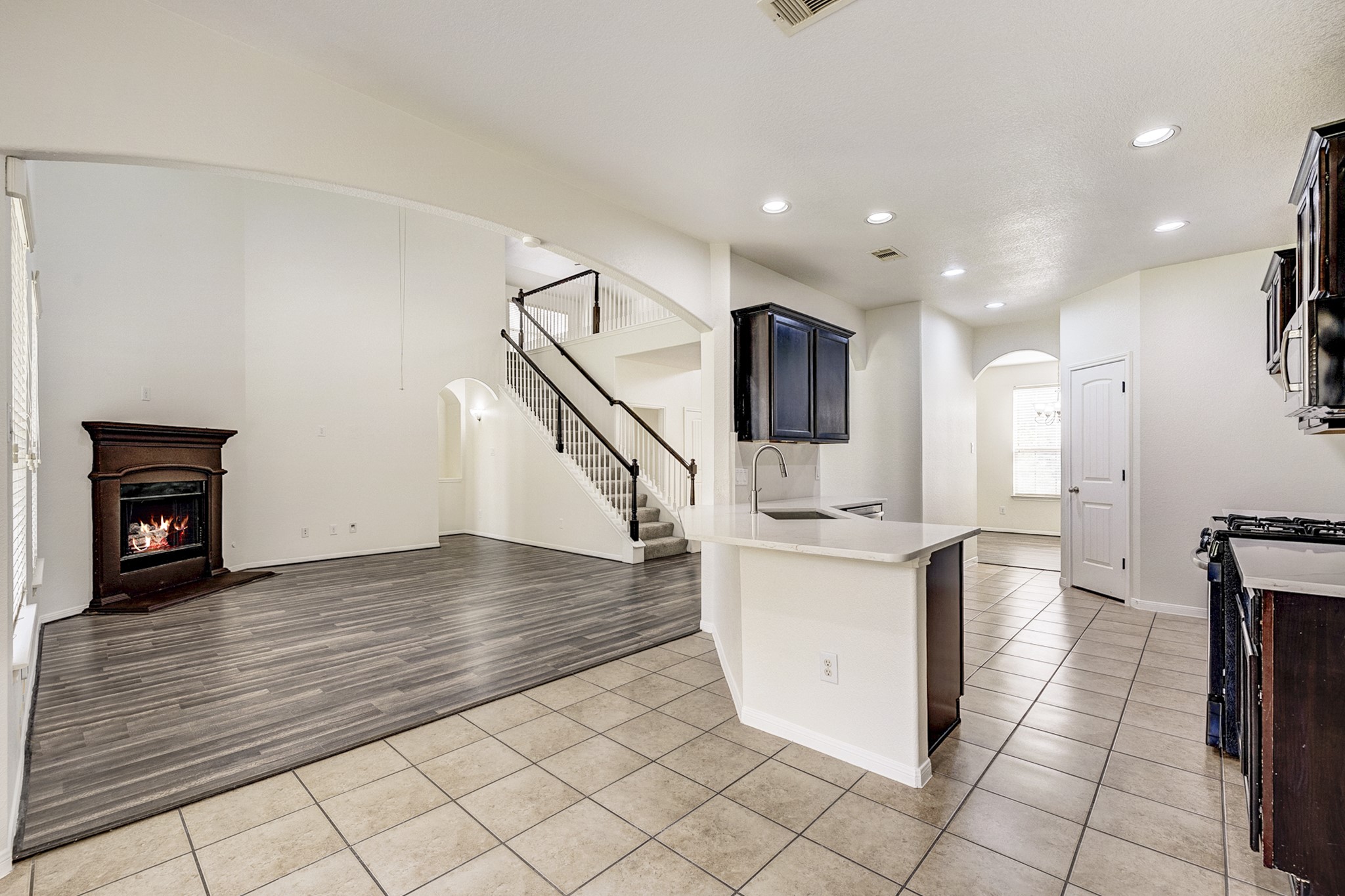 Spacious open-concept living area with a cozy fireplace, modern kitchen with an island, and elegant staircase leading to the upper level.