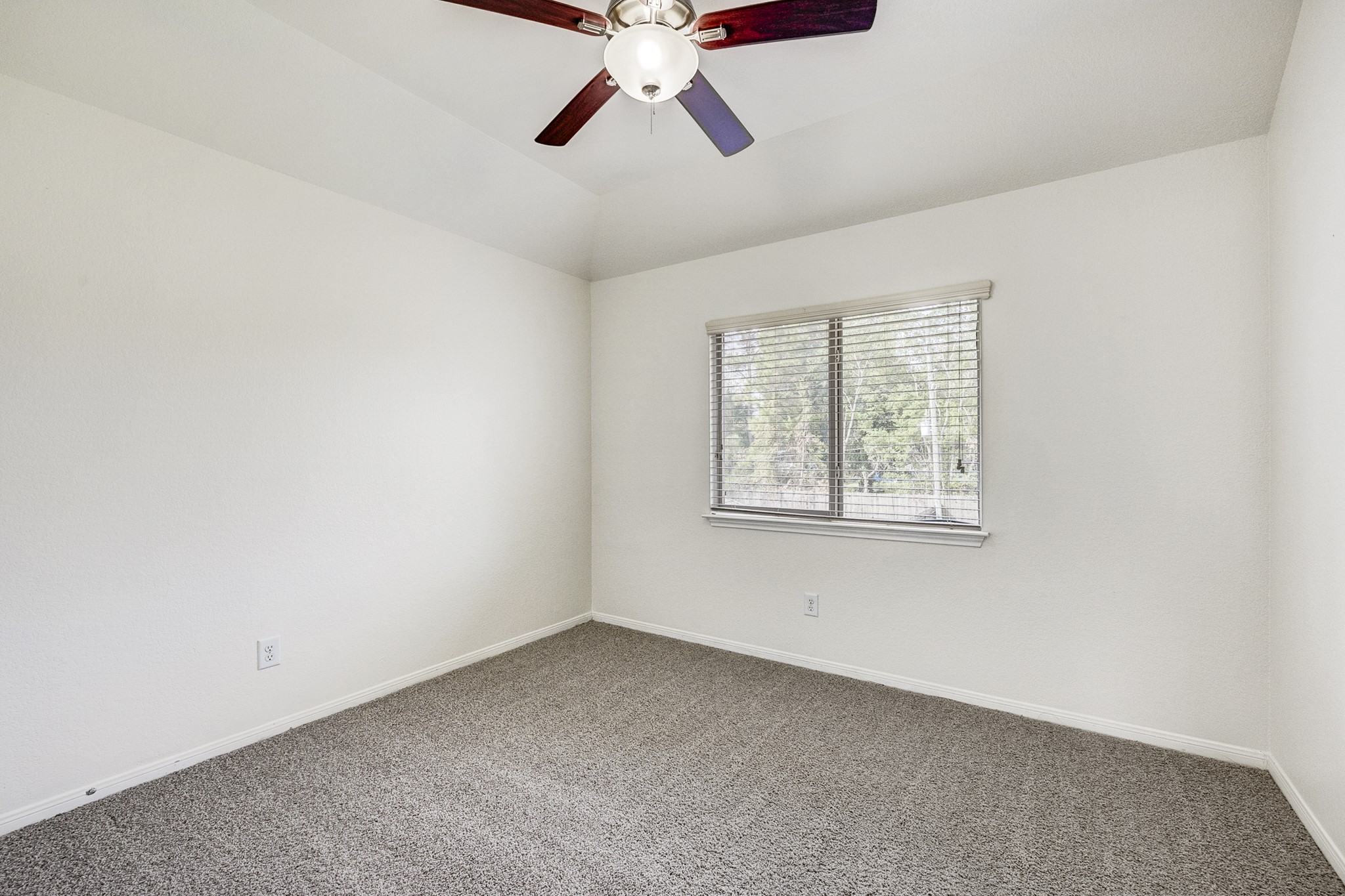 Bright and airy bedroom featuring a ceiling fan, plush carpeting, and a large window for natural light.