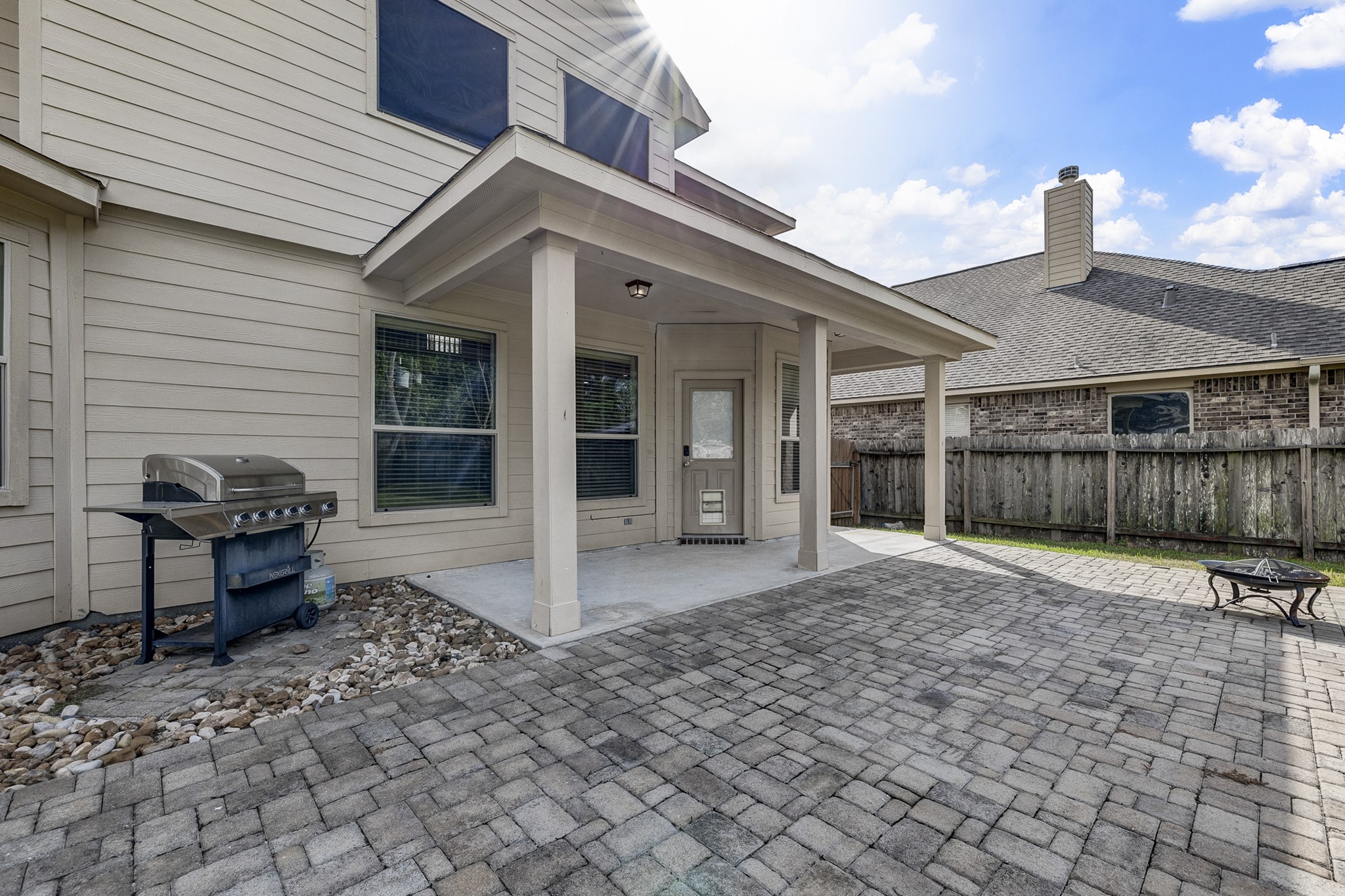 Spacious backyard patio with a covered area, perfect for outdoor grilling and entertaining, featuring a built-in BBQ and ample space for gatherings.
